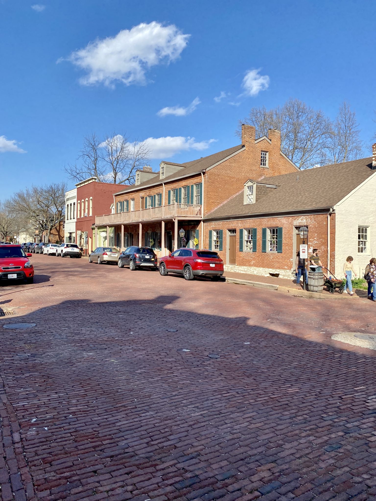 Cobblestone street lined with historic brick buildings under a sunny sky. - Katy Trail and Historic St. Charles Loop