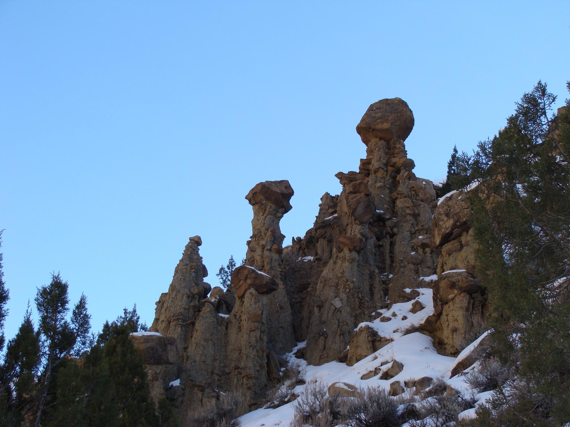 Unique rock pinnacles and snow-dusted trees against a bright blue sky.