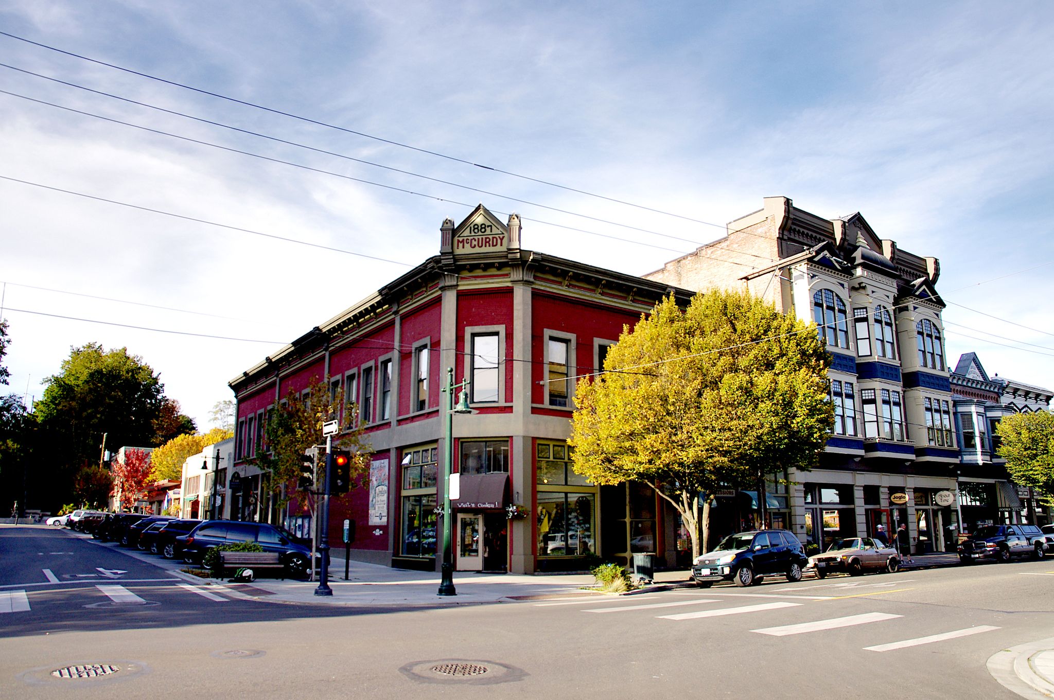 Historic red and blue buildings on a sunny street corner with parked cars. - Port Townsend – Port Townsend City Pier loop from Fort Townsend Historical State Park