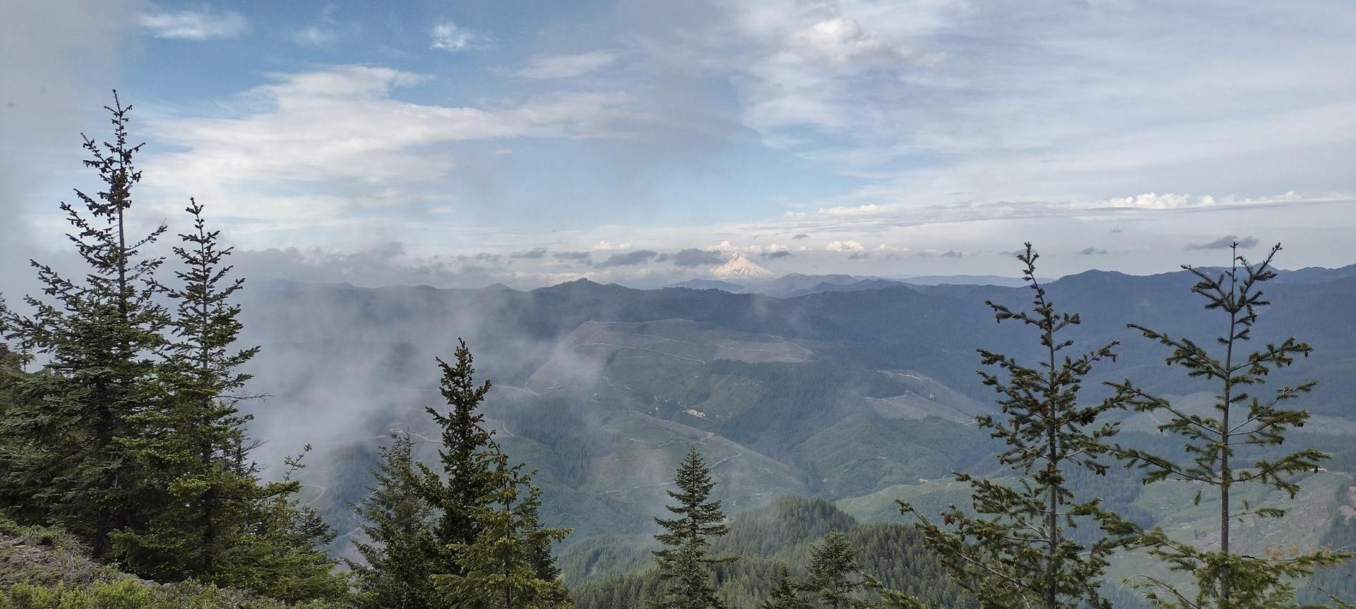 Panoramic view of distant mountains and valleys with scattered clouds.