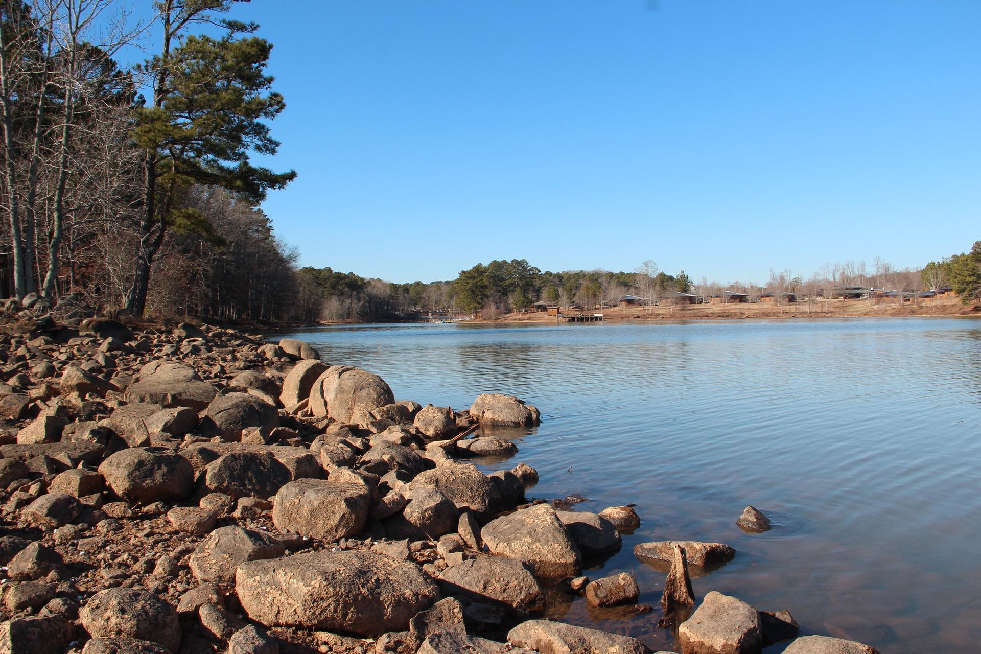 Rocky shoreline next to a calm lake under a bright blue sky.