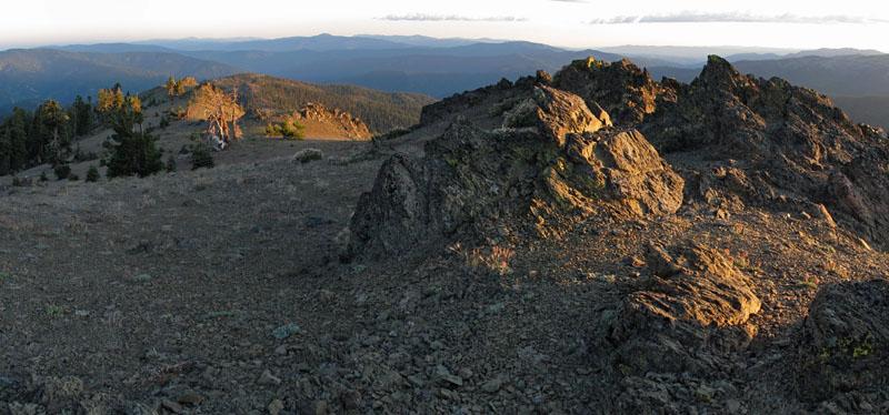 Rugged mountain ridge bathed in golden hour light, with distant peaks.