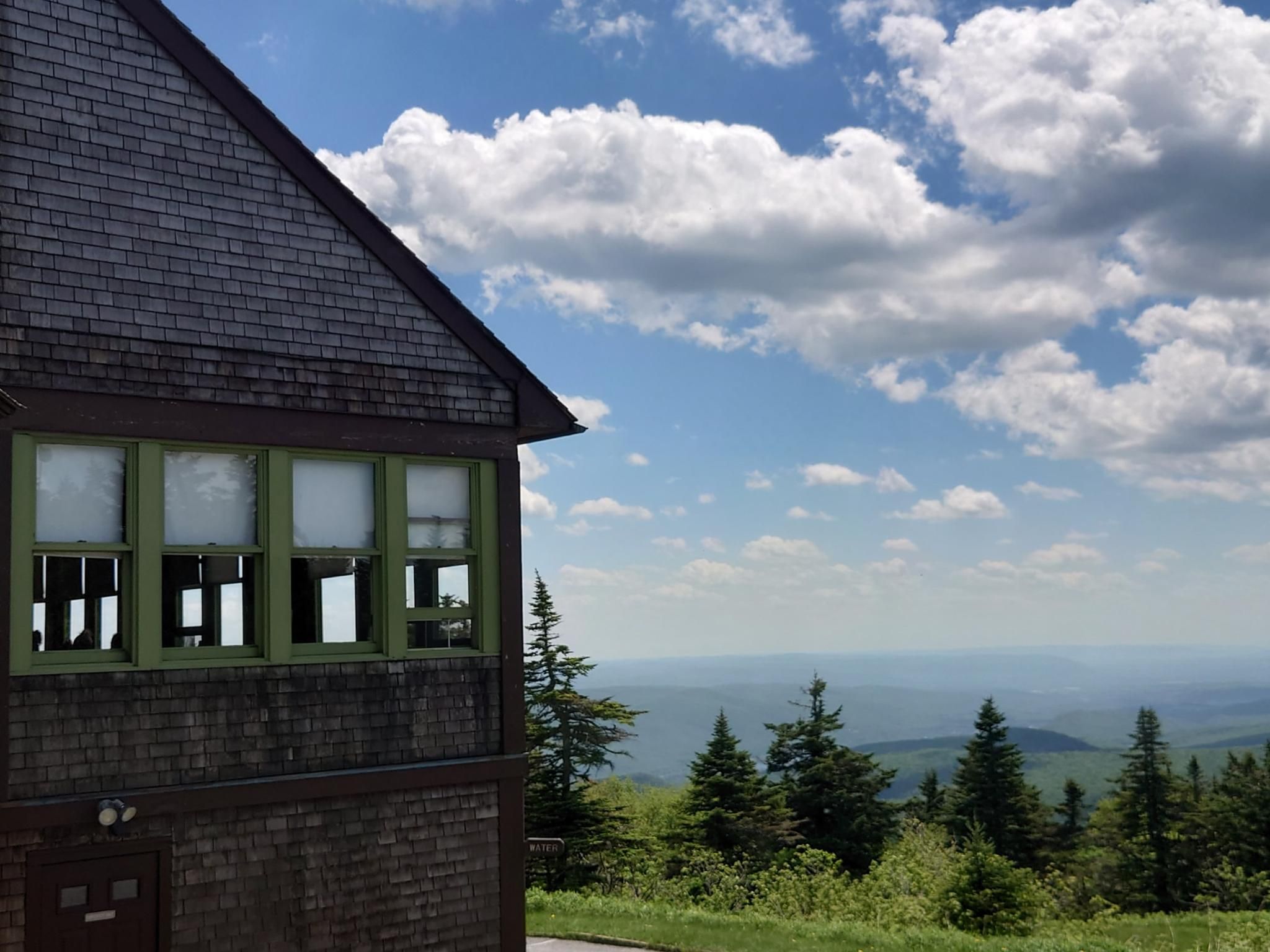 Shingled building overlooking a vast forested mountain landscape under a cloudy sky. - Mount Greylock and Stony Ledge via Hopper and Haley Farm Trails