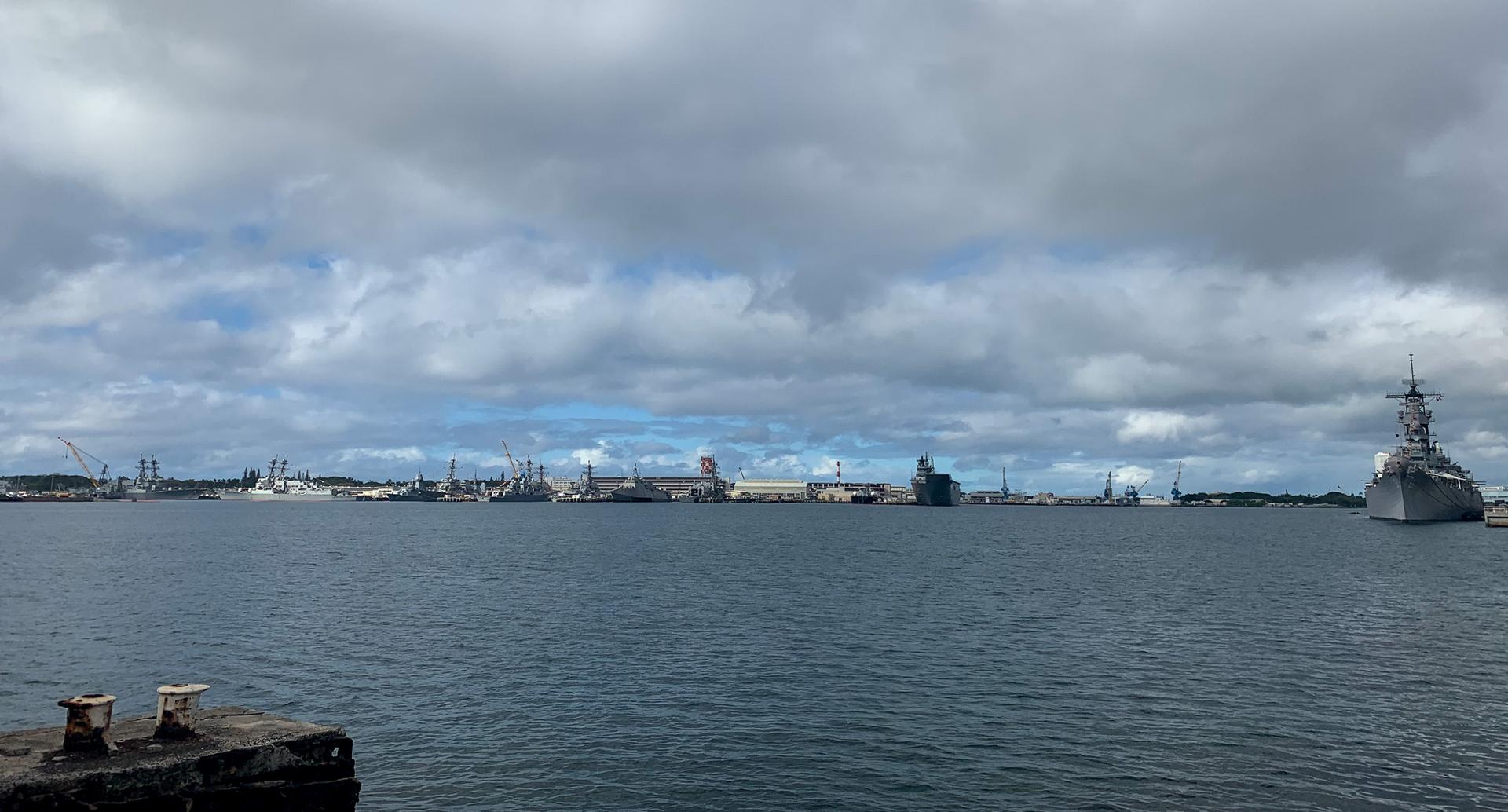 Overcast harbor scene with an industrial shoreline and a large gray ship.