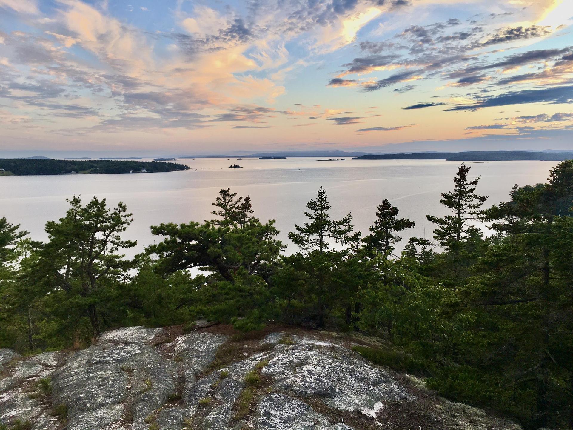 Panoramic view of a large water body with islands under a colorful sky.