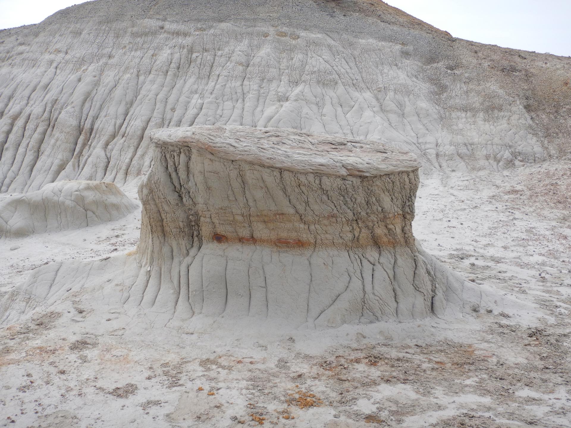 A large, rectangular rock formation sits on an eroded white landscape.