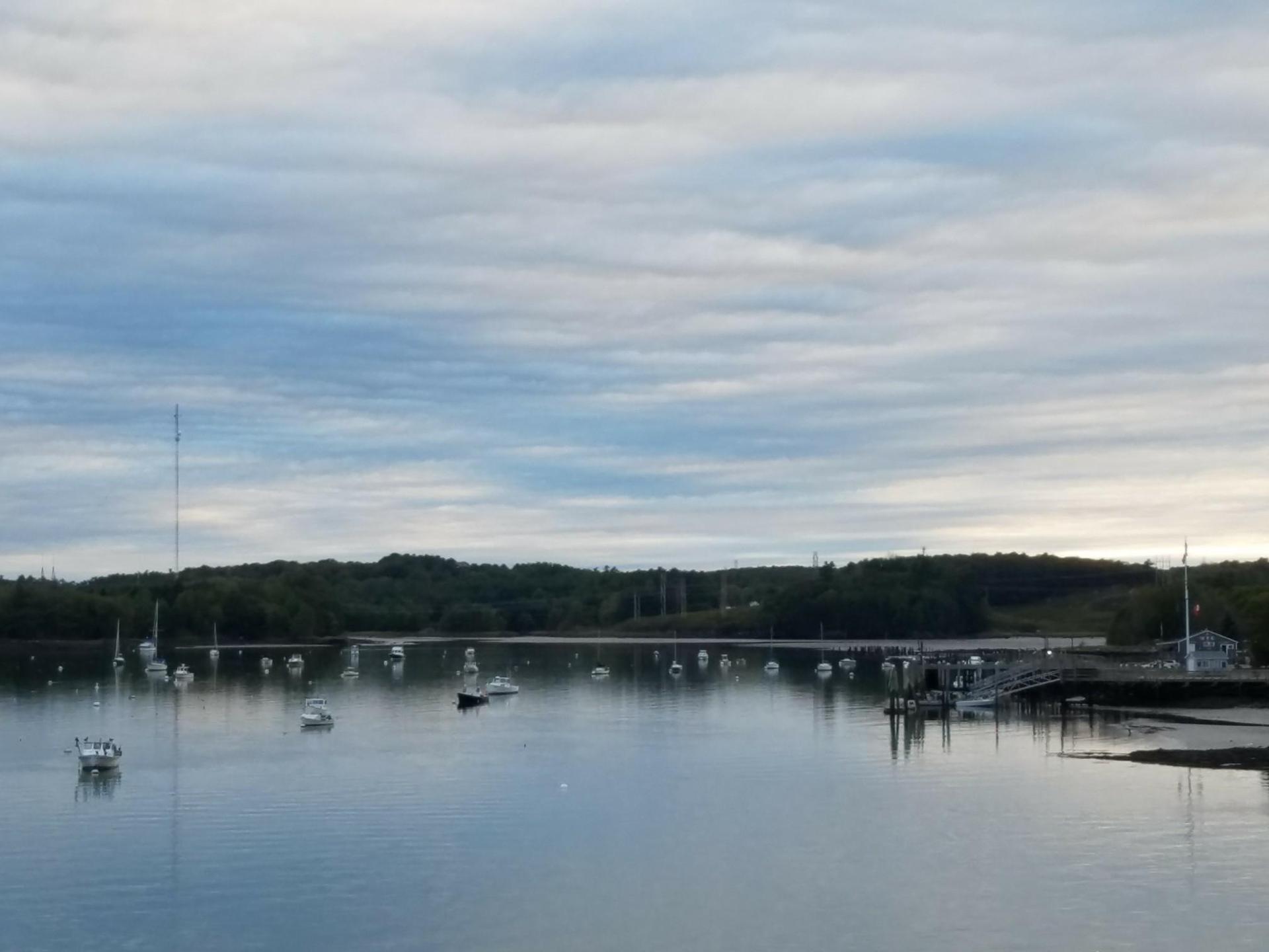 Numerous boats anchored in a calm bay under an overcast sky.