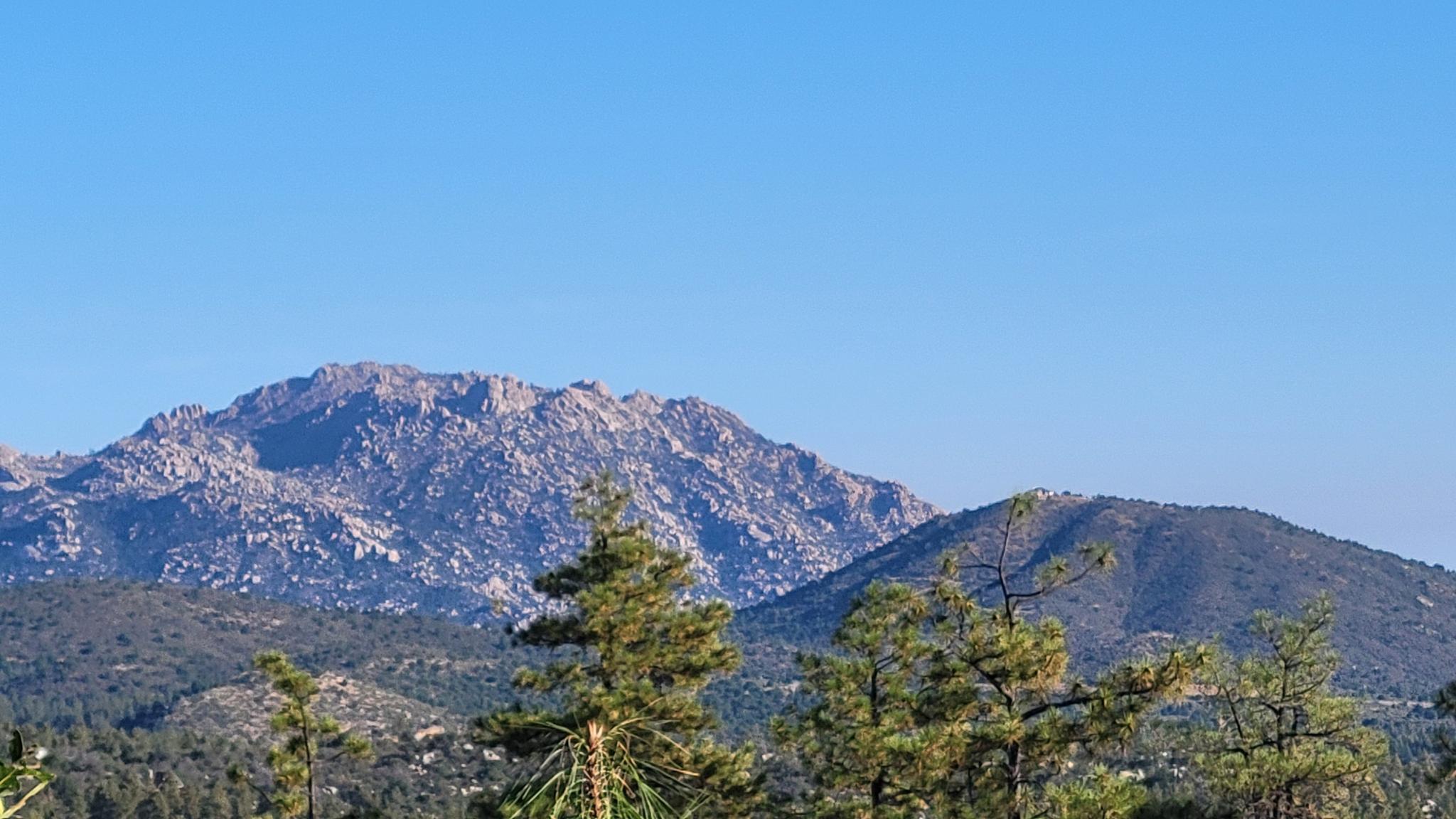 Rocky mountains and forested hills under a clear blue sky.