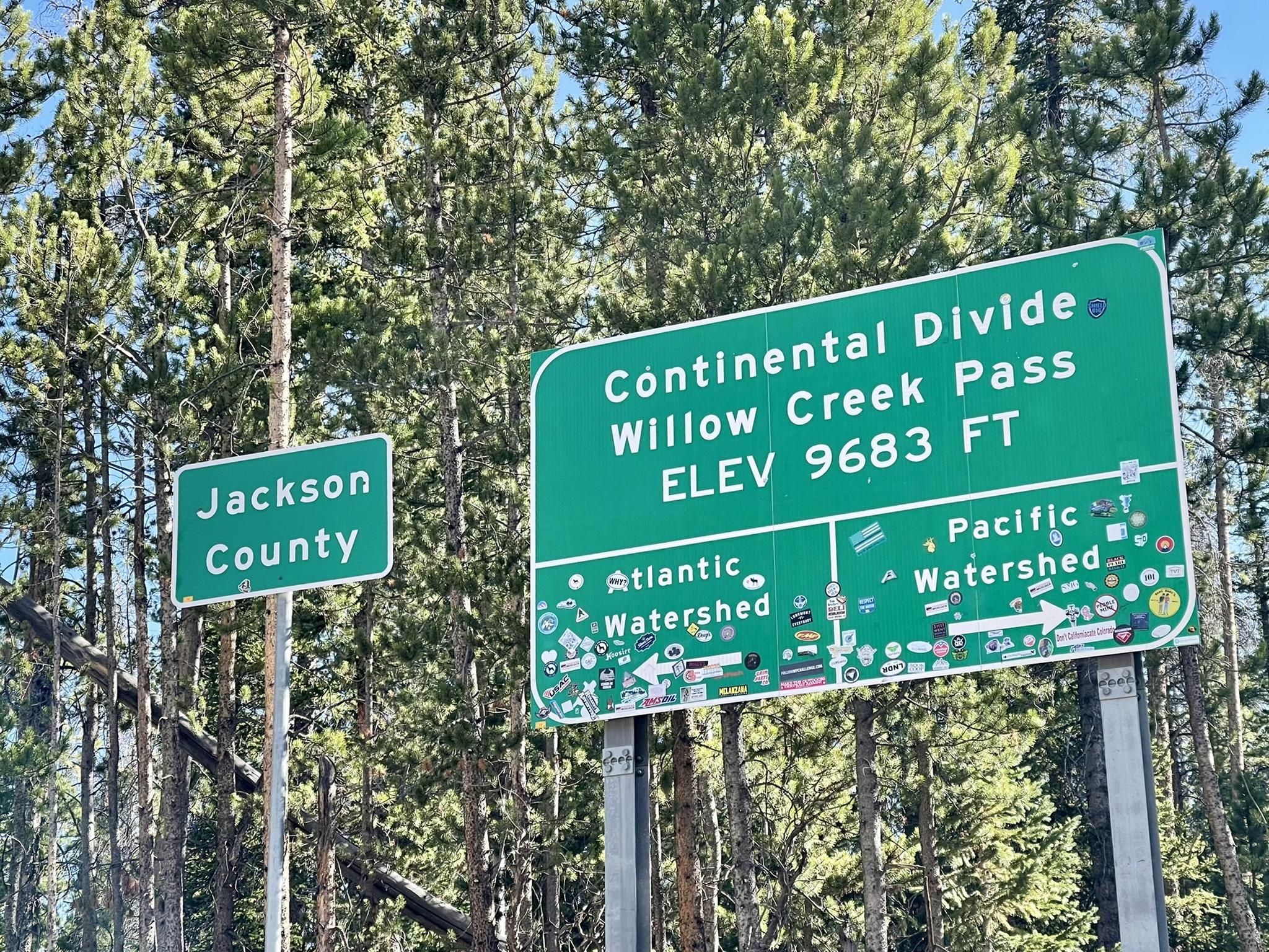 Two green road signs against a backdrop of tall pine trees. - TransAmerica Trail (Colorado)