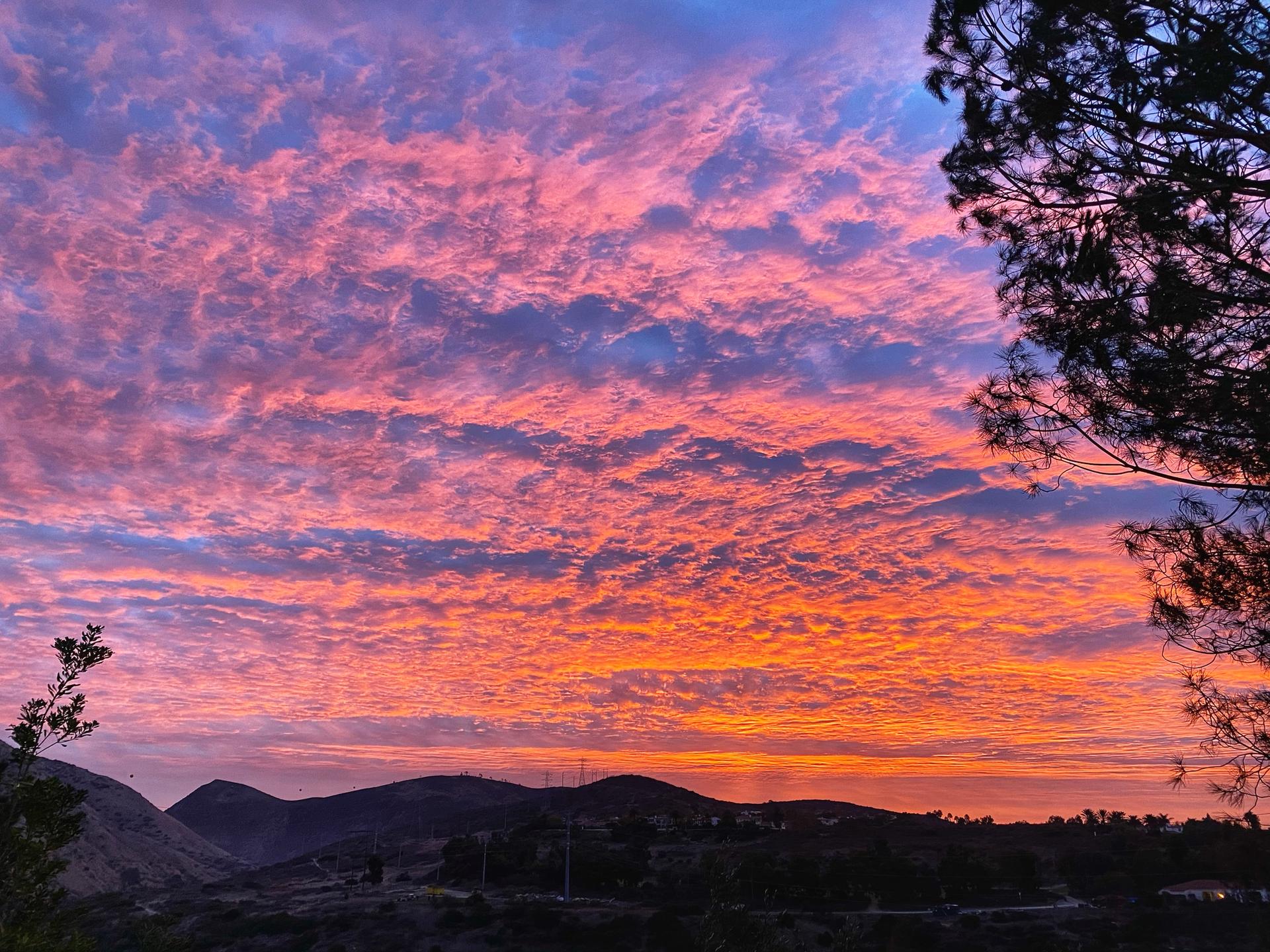 Vibrant orange and pink sunset clouds illuminate a mountain landscape.