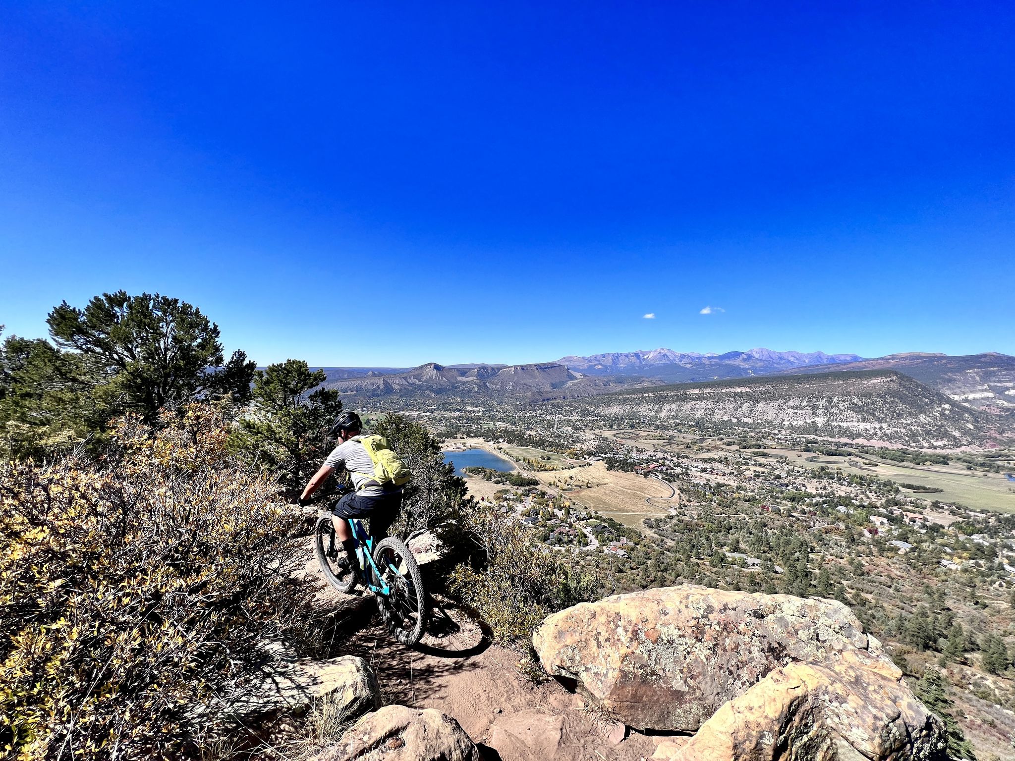 Mountain biker on a rocky trail overlooking a valley and distant mountains. - Raiders Ridge Trail