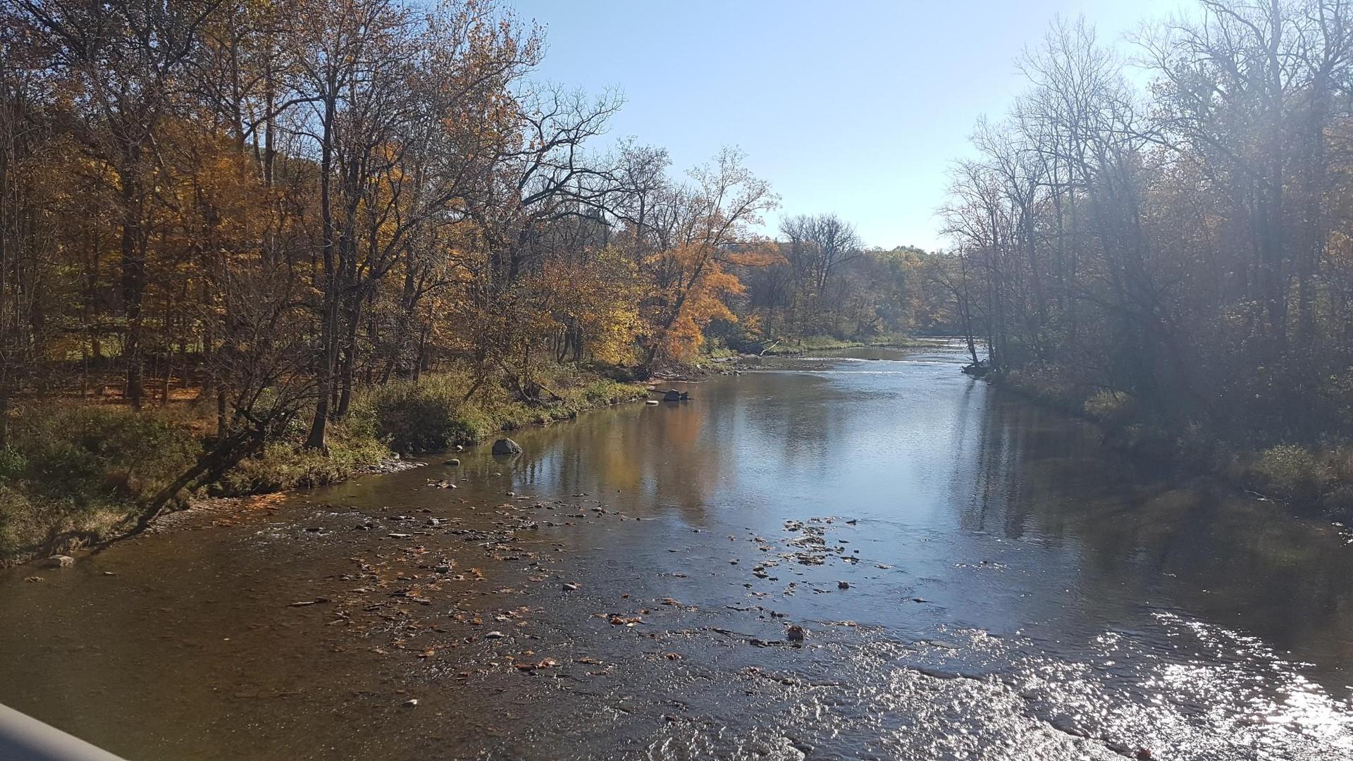 Sunny autumn river scene with colorful trees reflecting on the water.