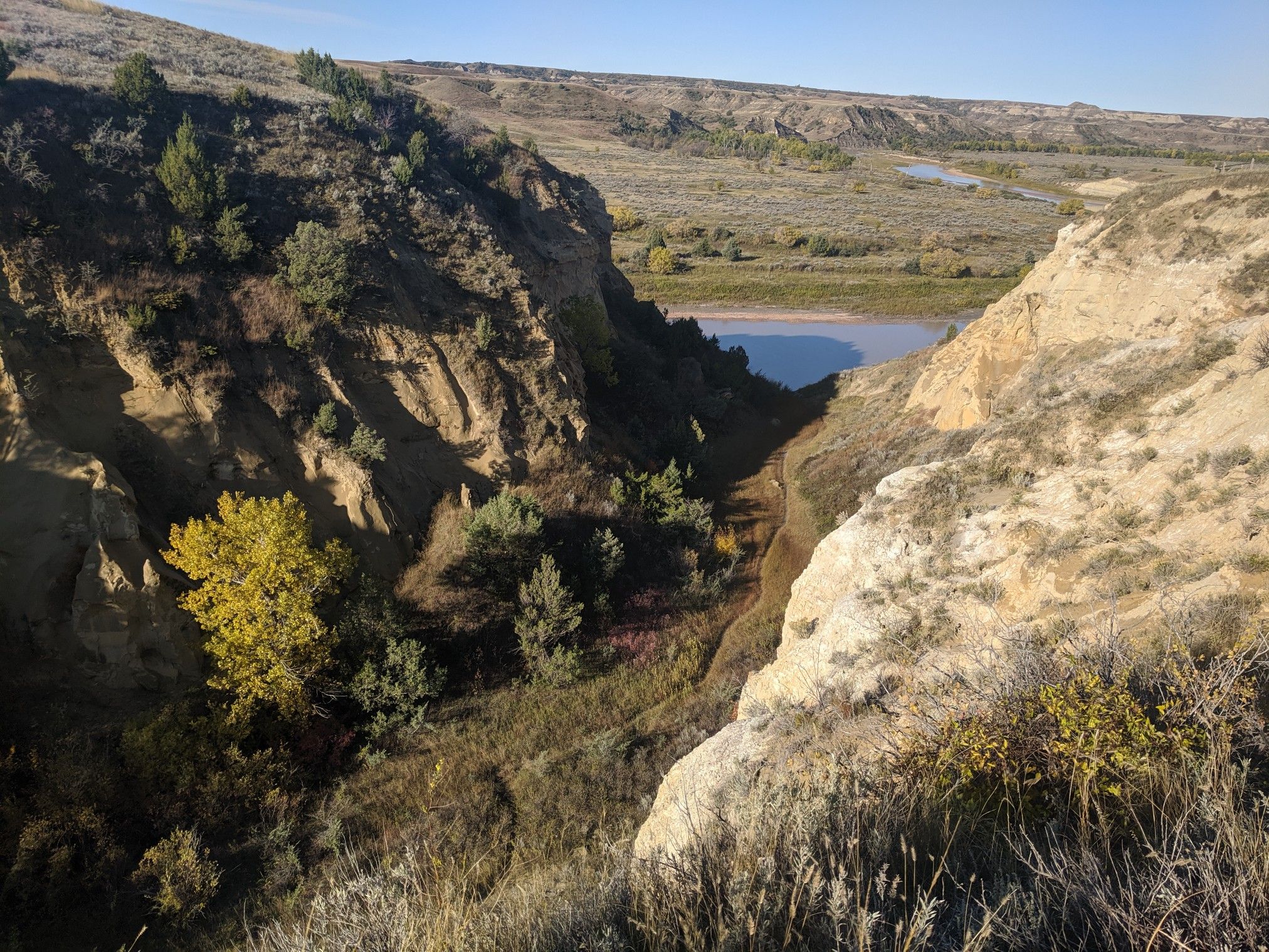 A deep, rocky canyon with a river visible in the distant valley. - Wind Canyon Trail