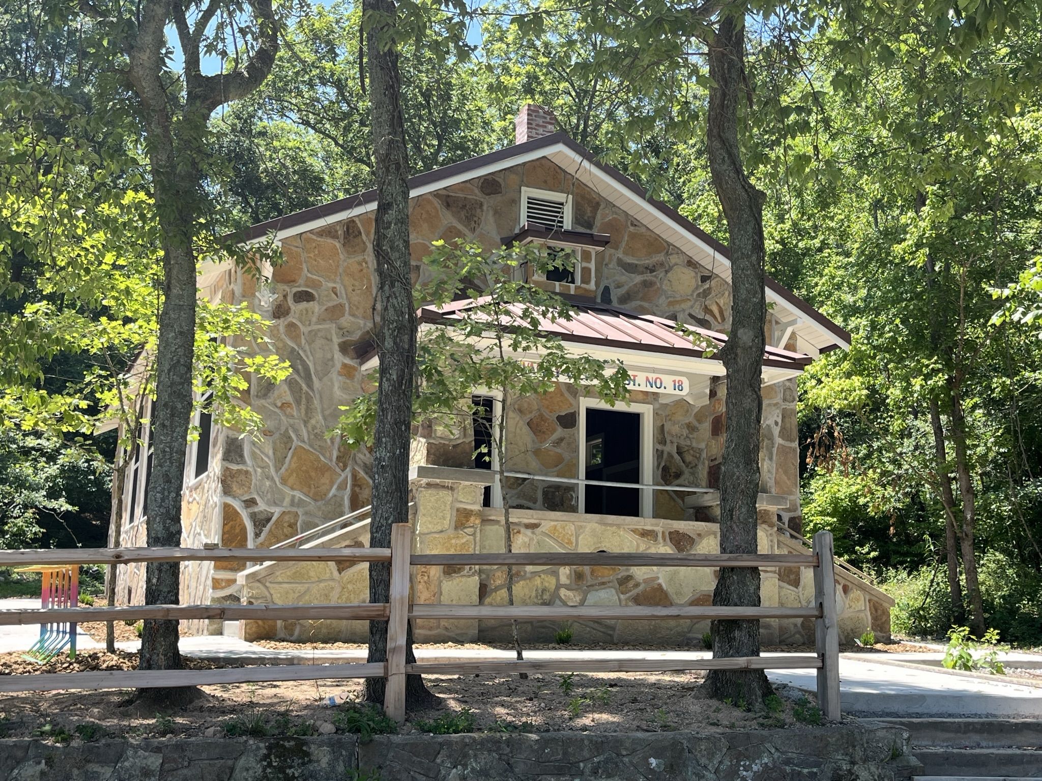 A stone building with a red roof stands among green trees. - Traverse and Mother Necessity Loop