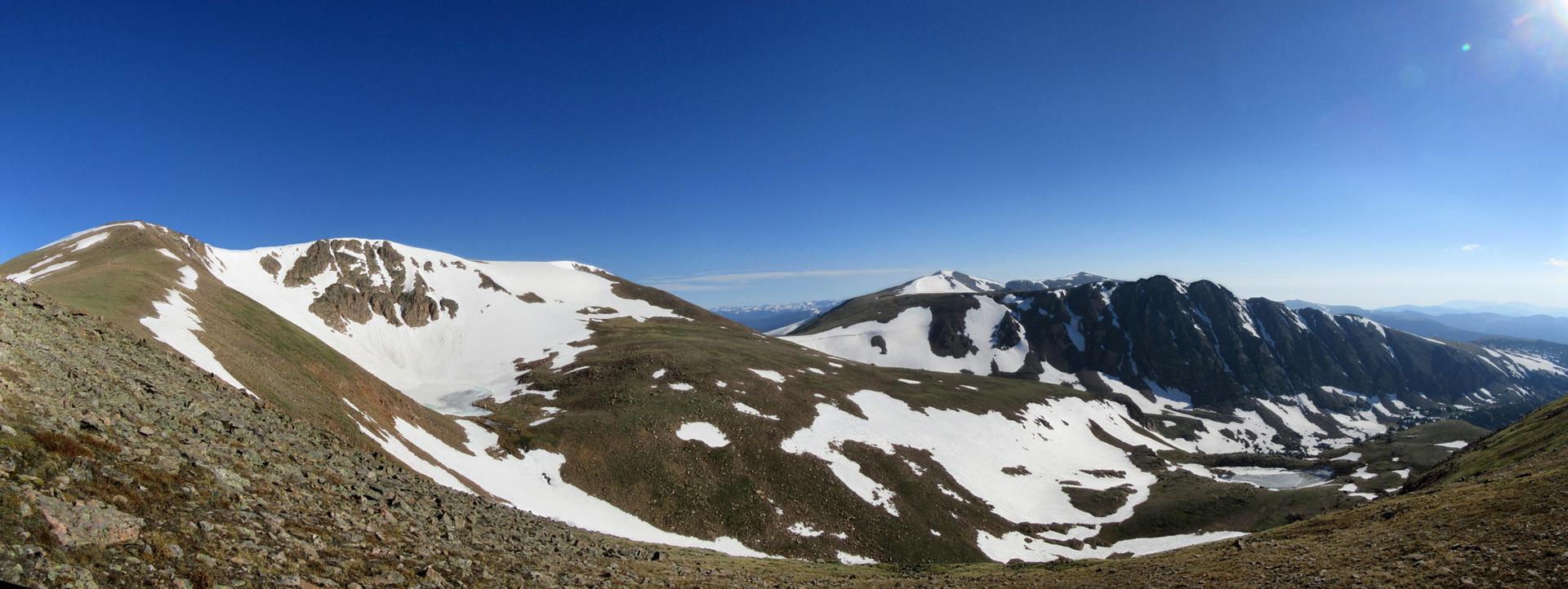 Panoramic view of snow-covered mountains under a clear blue sky.