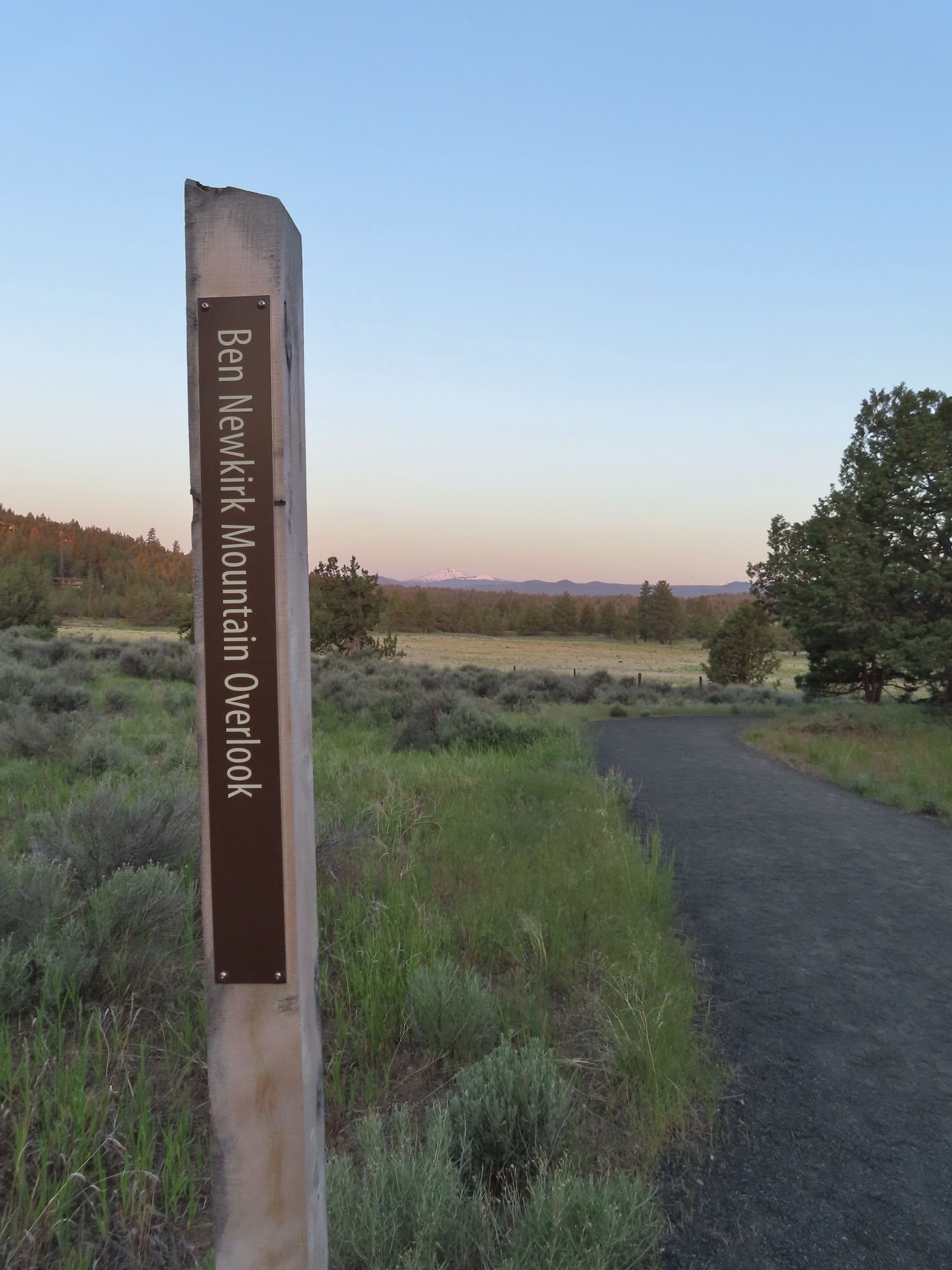 A signpost with text next to a dirt path overlooking a field at dawn. - Juniper, Sage Flat, and Canyon Loop