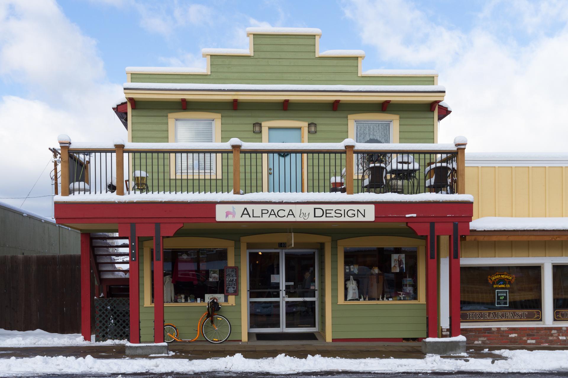 Green and red two-story shop building with snow on the ground.
