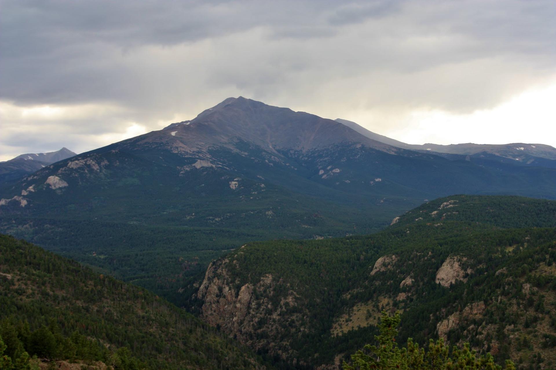 Vast forested mountain range under an overcast sky, with a prominent peak.
