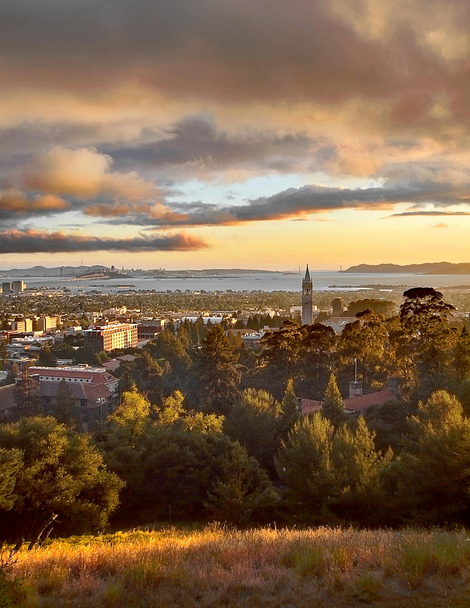 Cityscape and bay at sunset with dramatic clouds and a prominent clock tower.