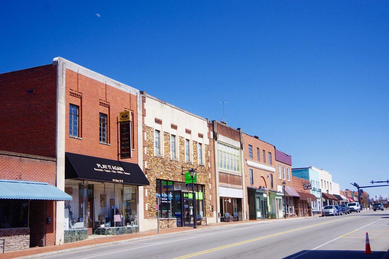 Row of brick storefronts along a street under a clear blue sky.