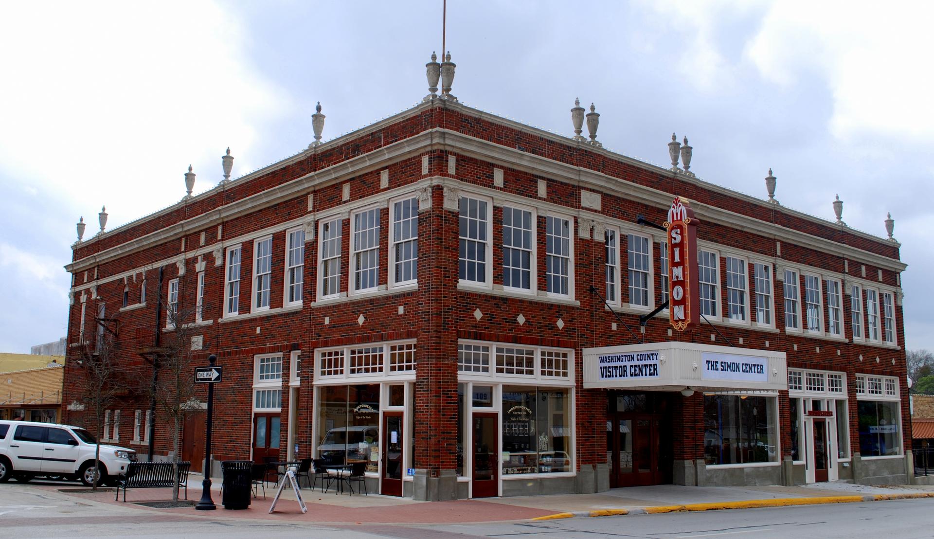 Large red brick building with many windows and a prominent sign under cloudy skies.