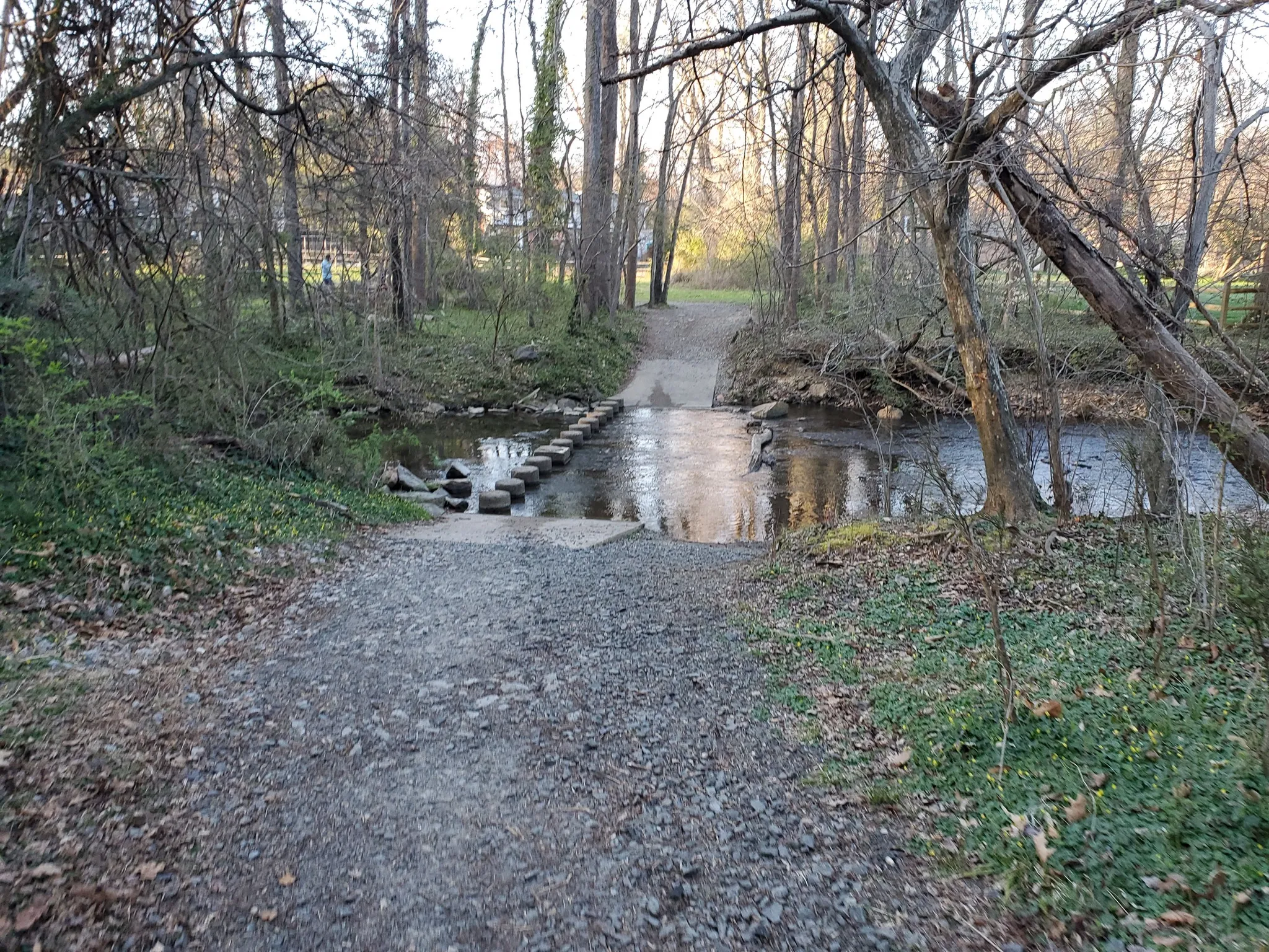 Gravel path approaches stepping stones crossing a stream in a bare forest. - Holmes Run Trail and Roundtree Park Loop