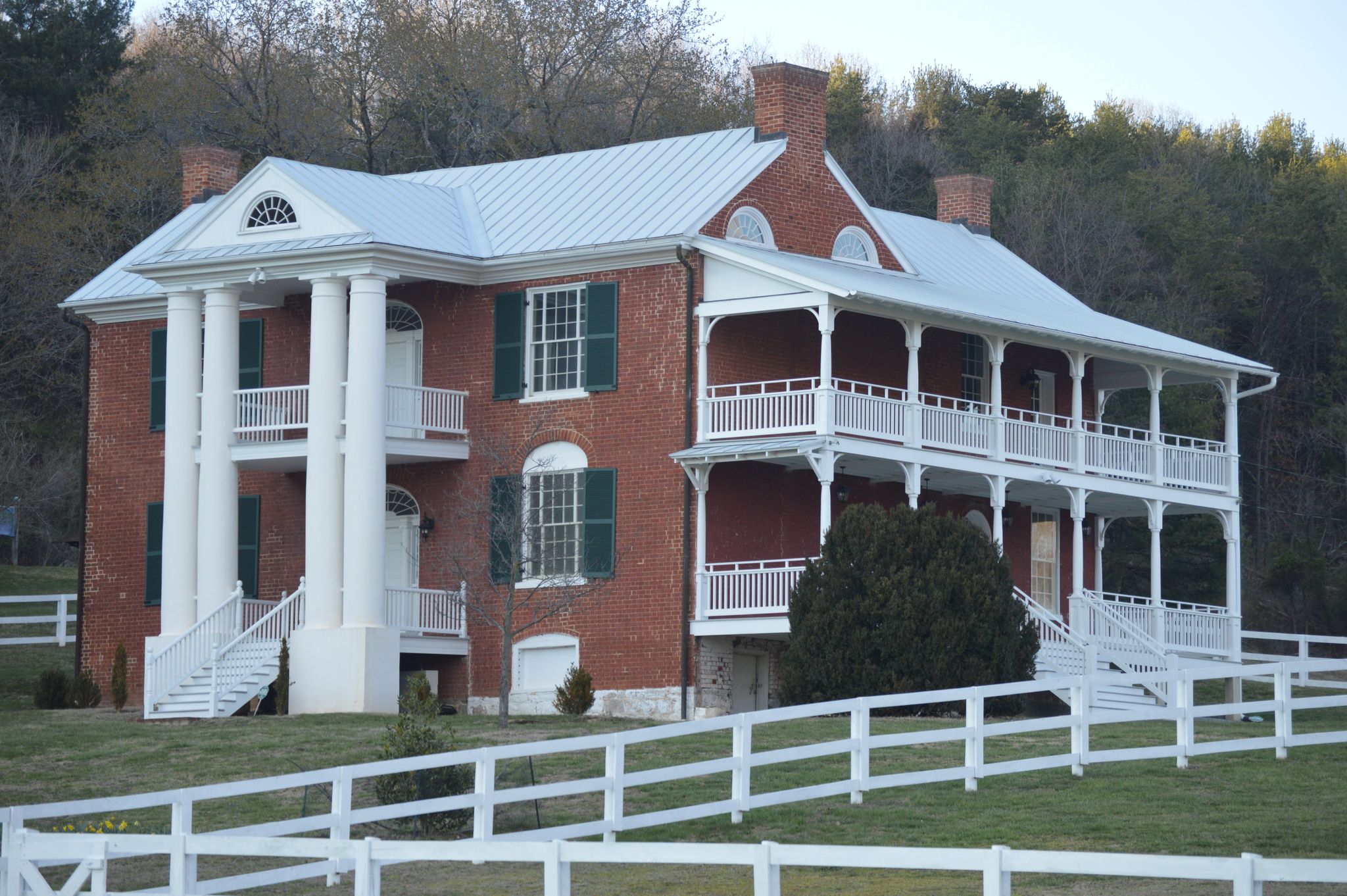 A large, historic brick house with white columns and porches on a grassy hill. - Buena Vista Riverwalk & Glen Maury Park loop