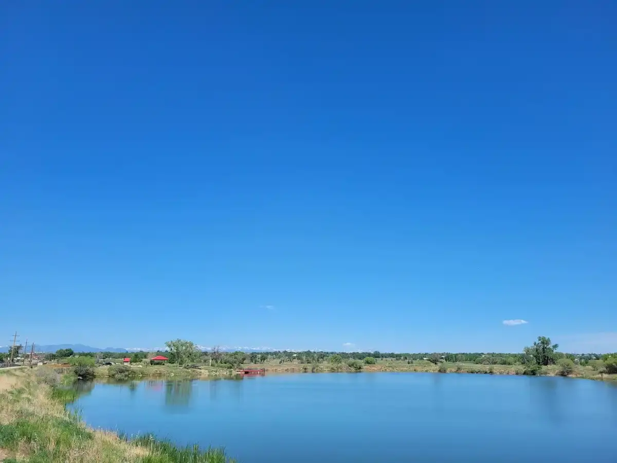 Serene blue lake surrounded by green banks under a clear, bright sky.