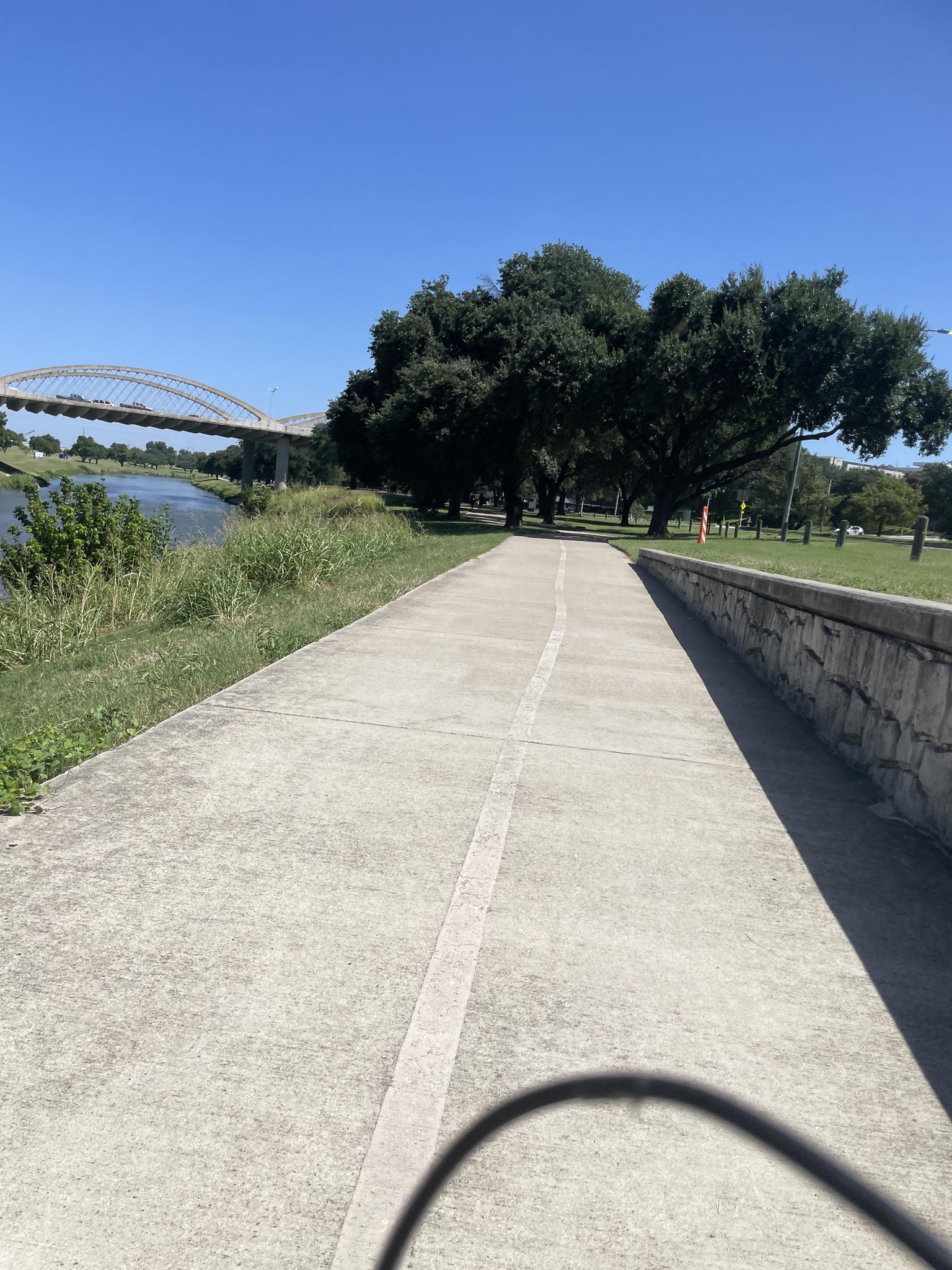 A paved path leads towards a large bridge over a river.