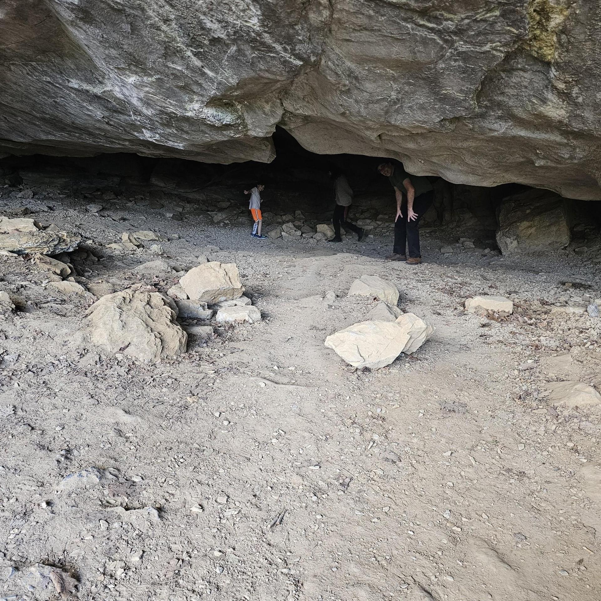 Three people exploring a dark, rocky cave interior.