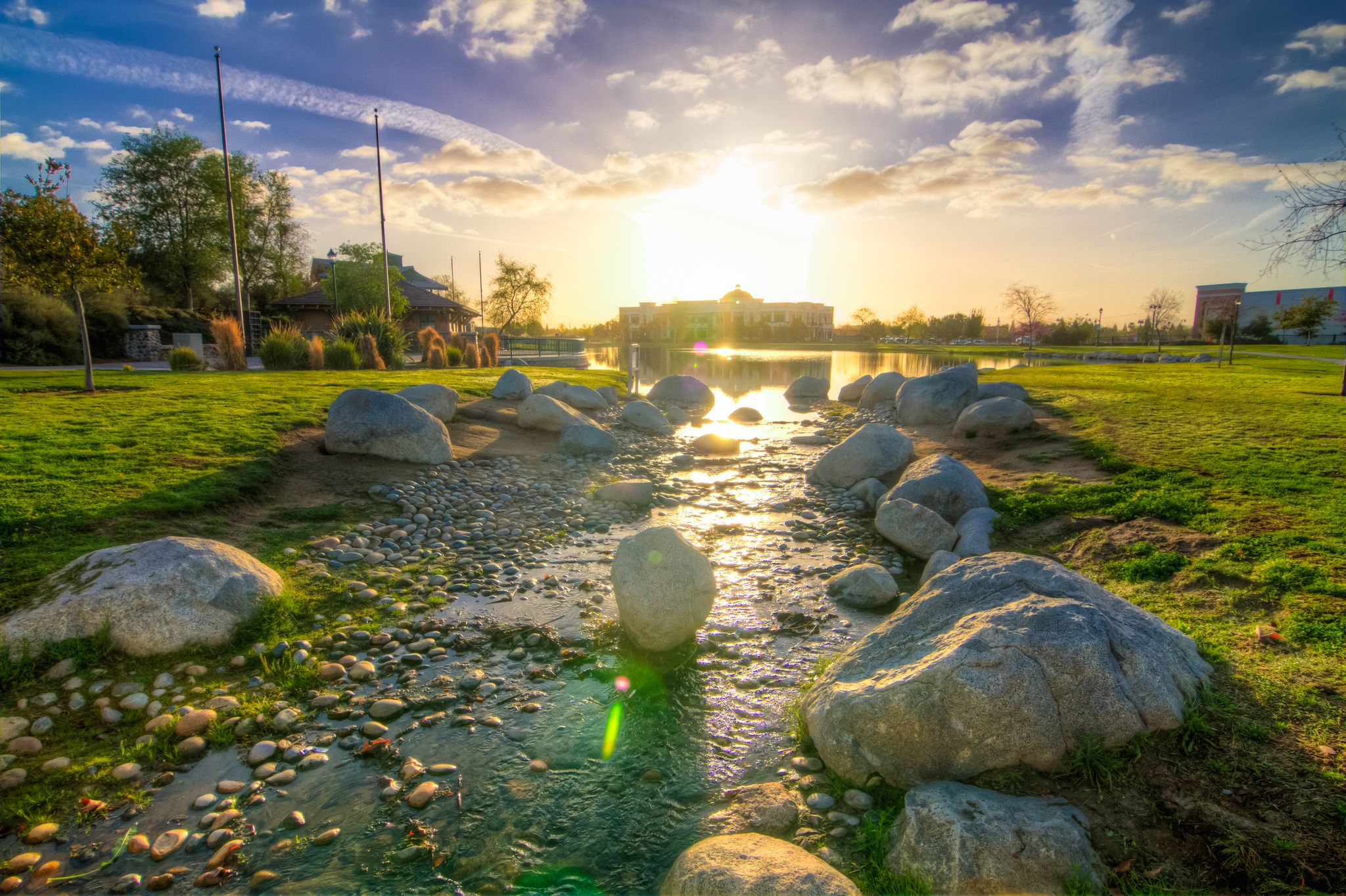 Golden hour light illuminates a rocky stream flowing through a vibrant green park. - River Walk Loop at Kern River