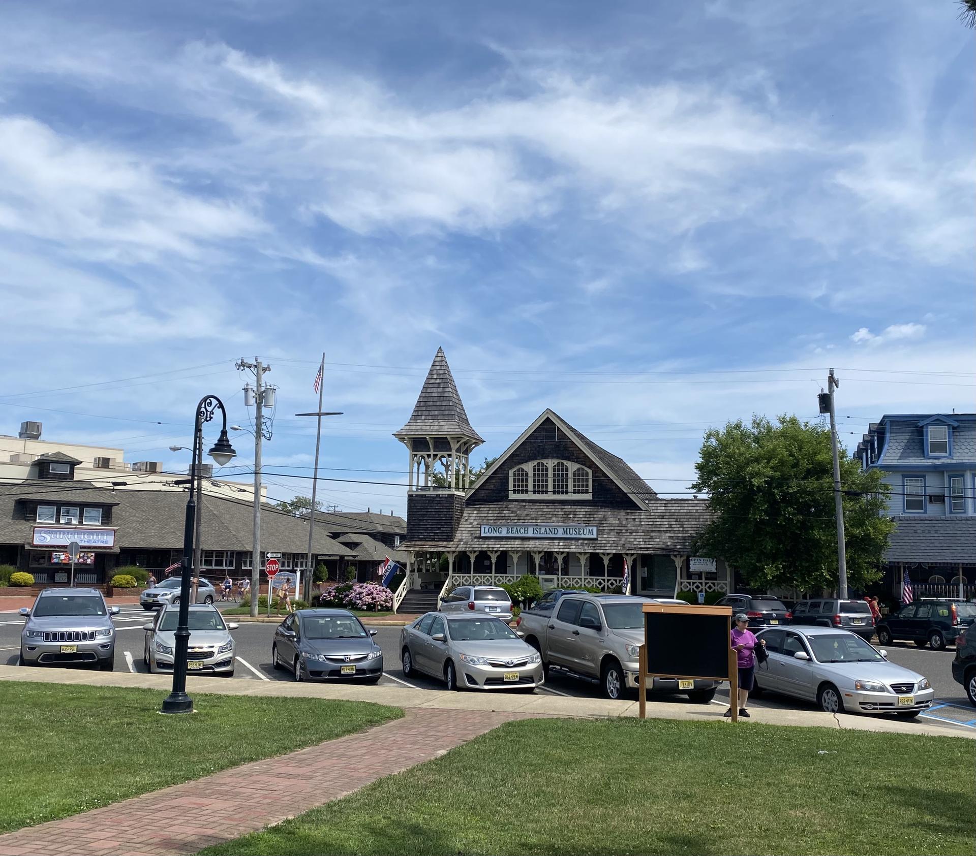 Historic building with a steeple, cars parked on a sunny day.