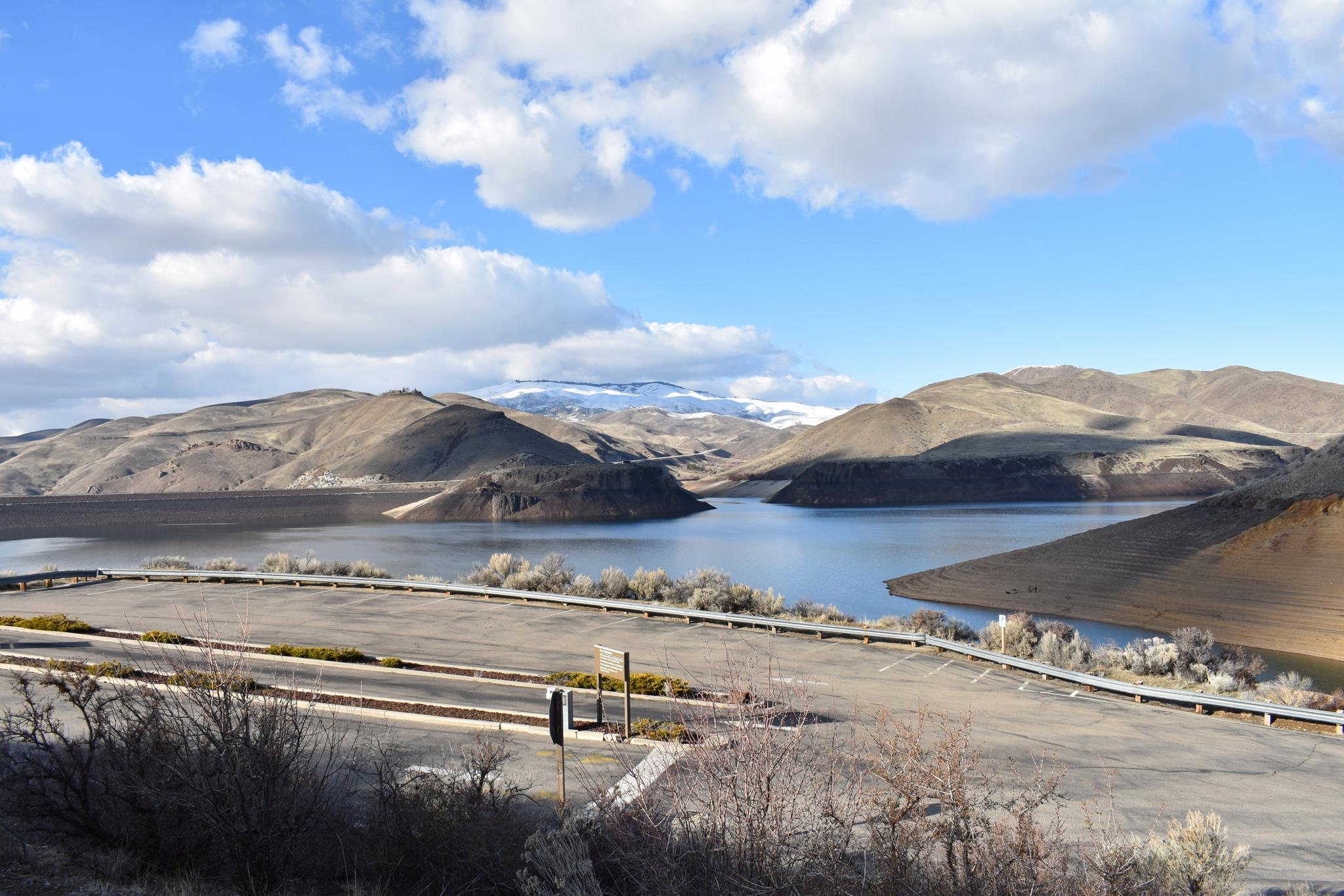 Expansive lake surrounded by arid mountains under a partly cloudy sky.