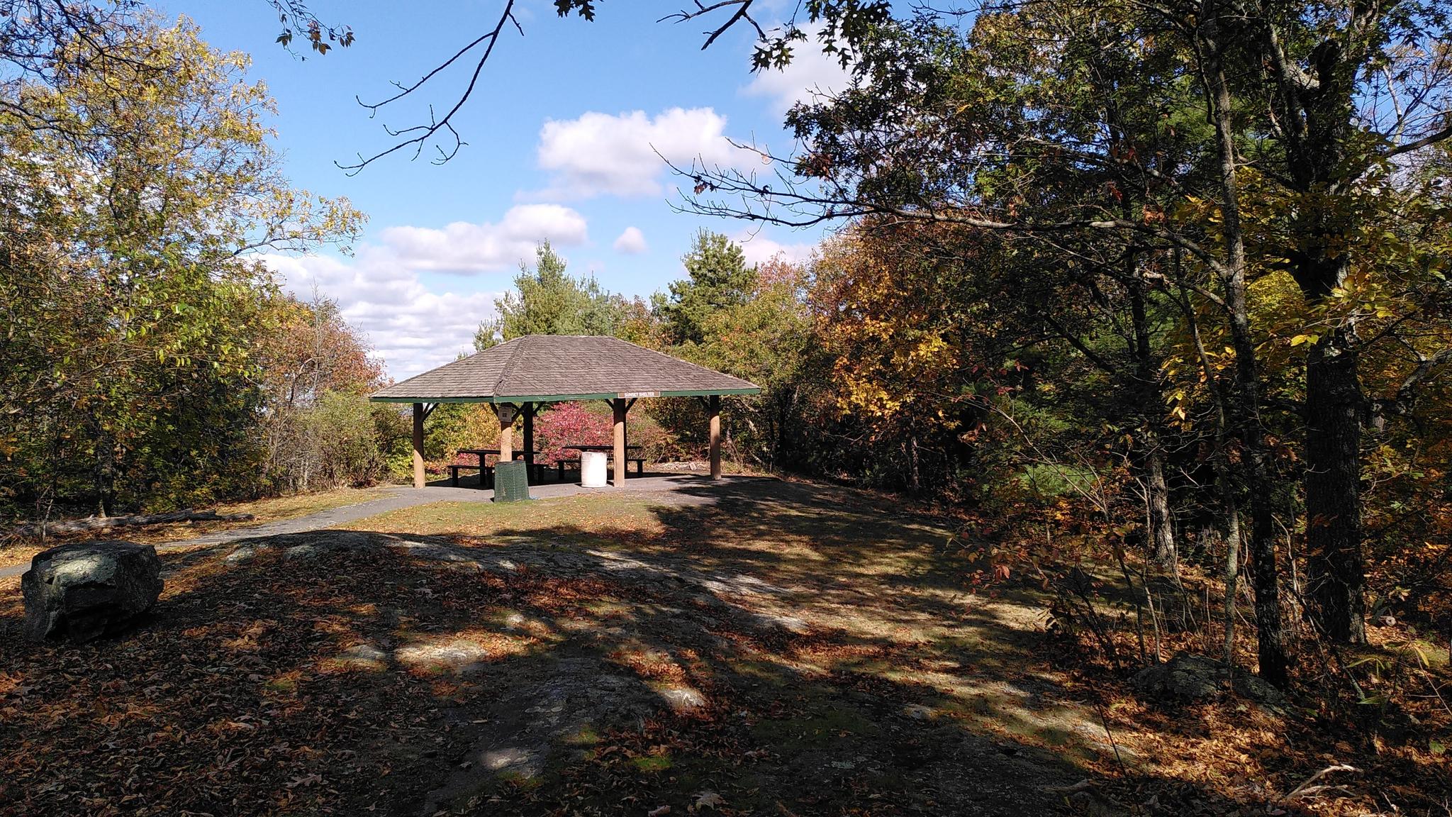A sunny autumn day with a gazebo surrounded by colorful trees and blue sky.