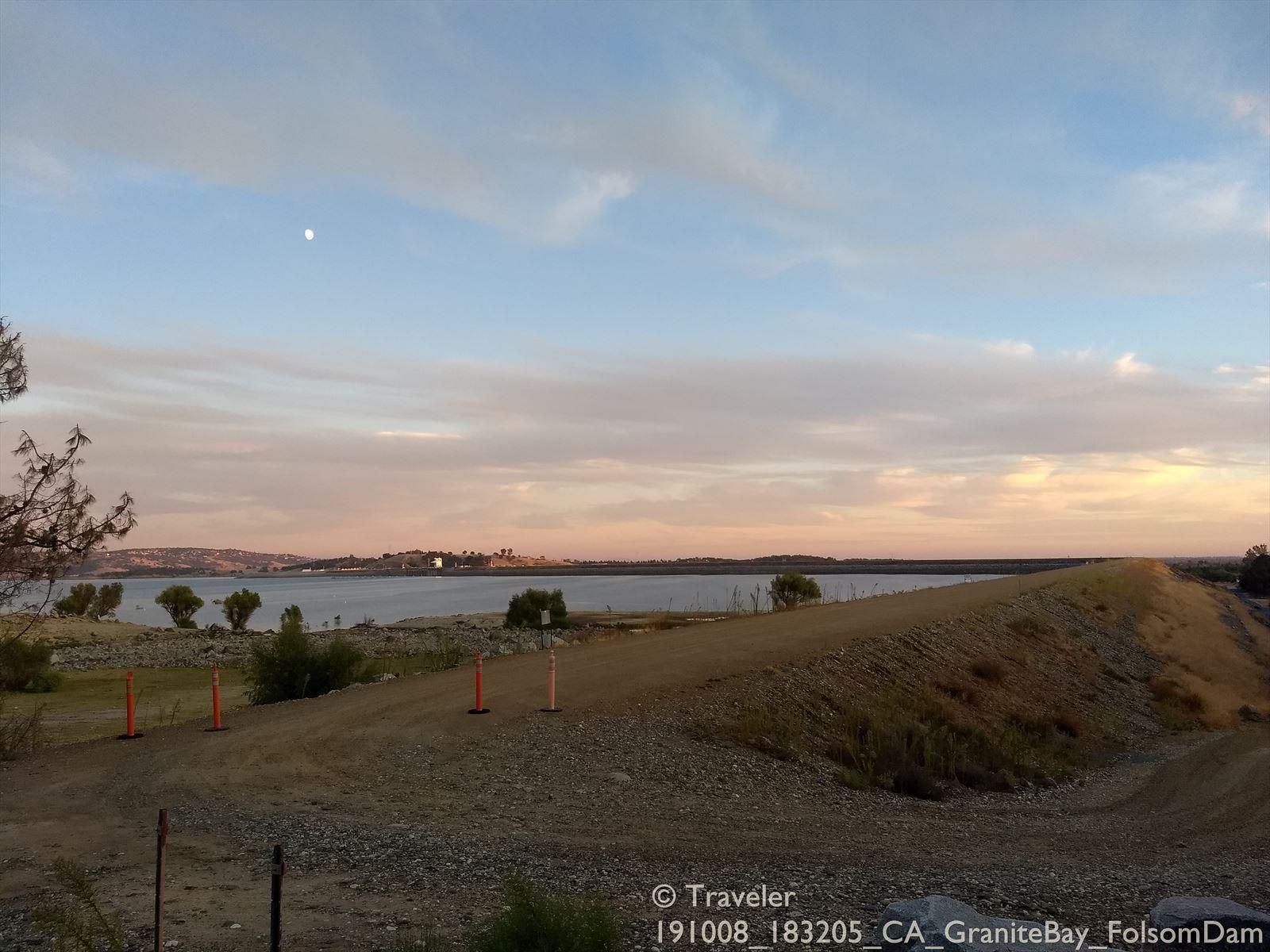 A lake at dusk with a moon, distant hills, and orange cones. - American River Bike Trail via South Cirby Way loop