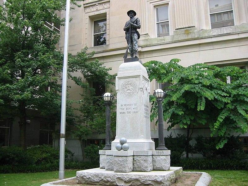 A stone monument with a soldier statue in front of a building.