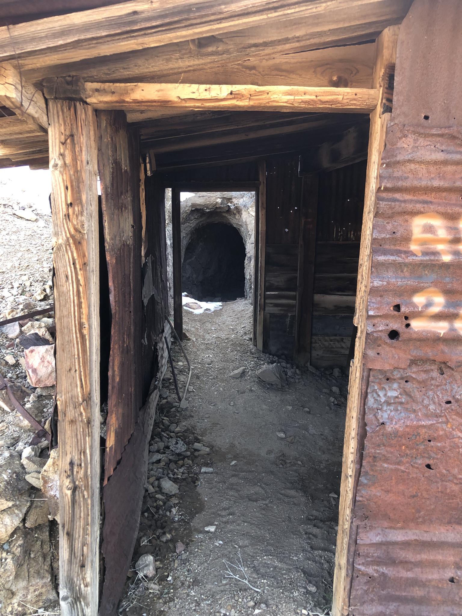Rustic wooden and metal structure leading into a dark mine tunnel.