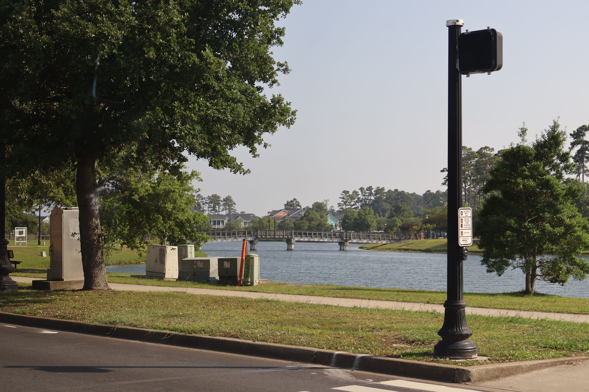 A calm lake with a distant bridge, seen from a grassy roadside. - Market Common Trail to Warbird Park loop