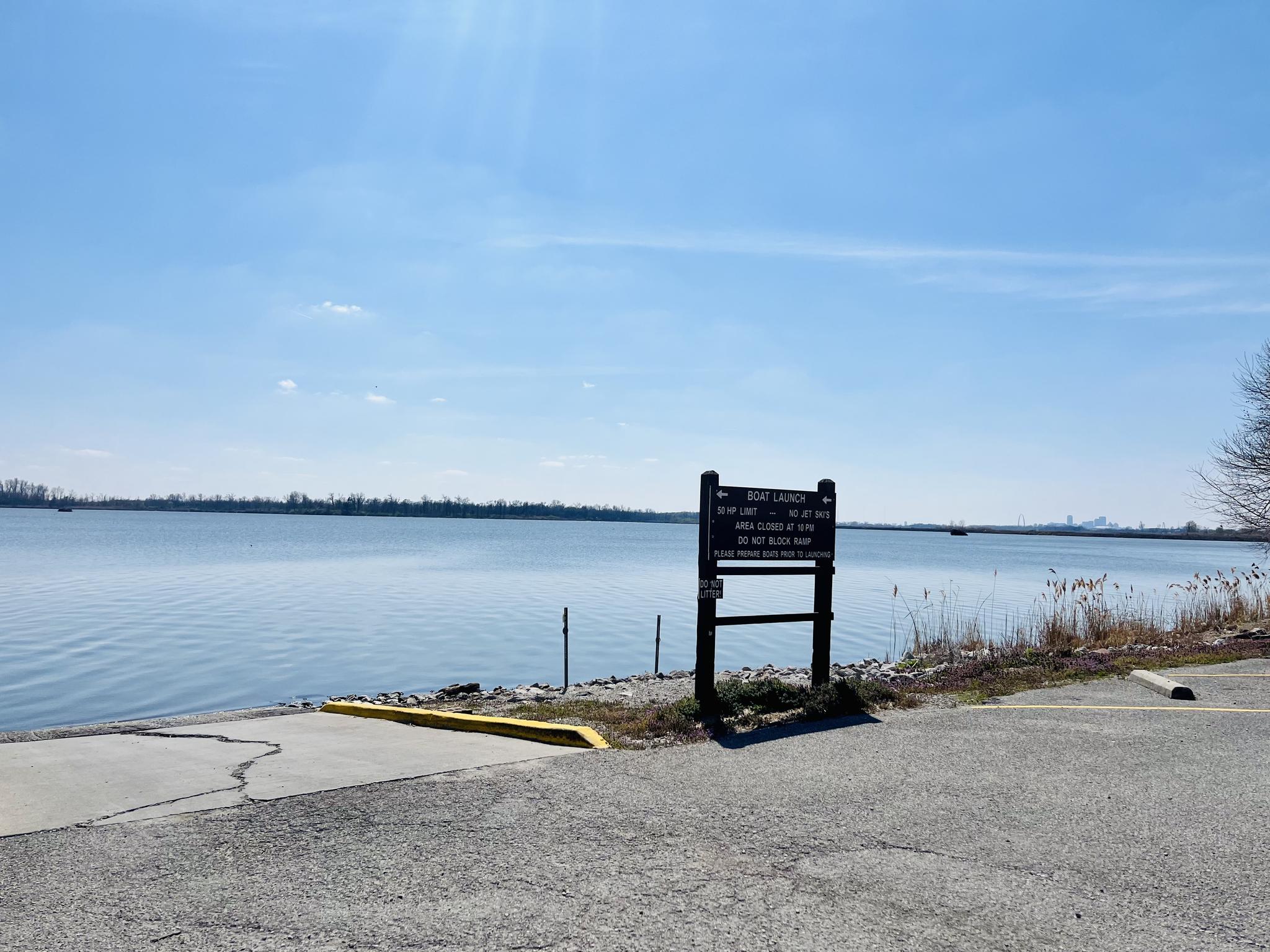 Boat ramp leading to a wide body of water on a sunny day.