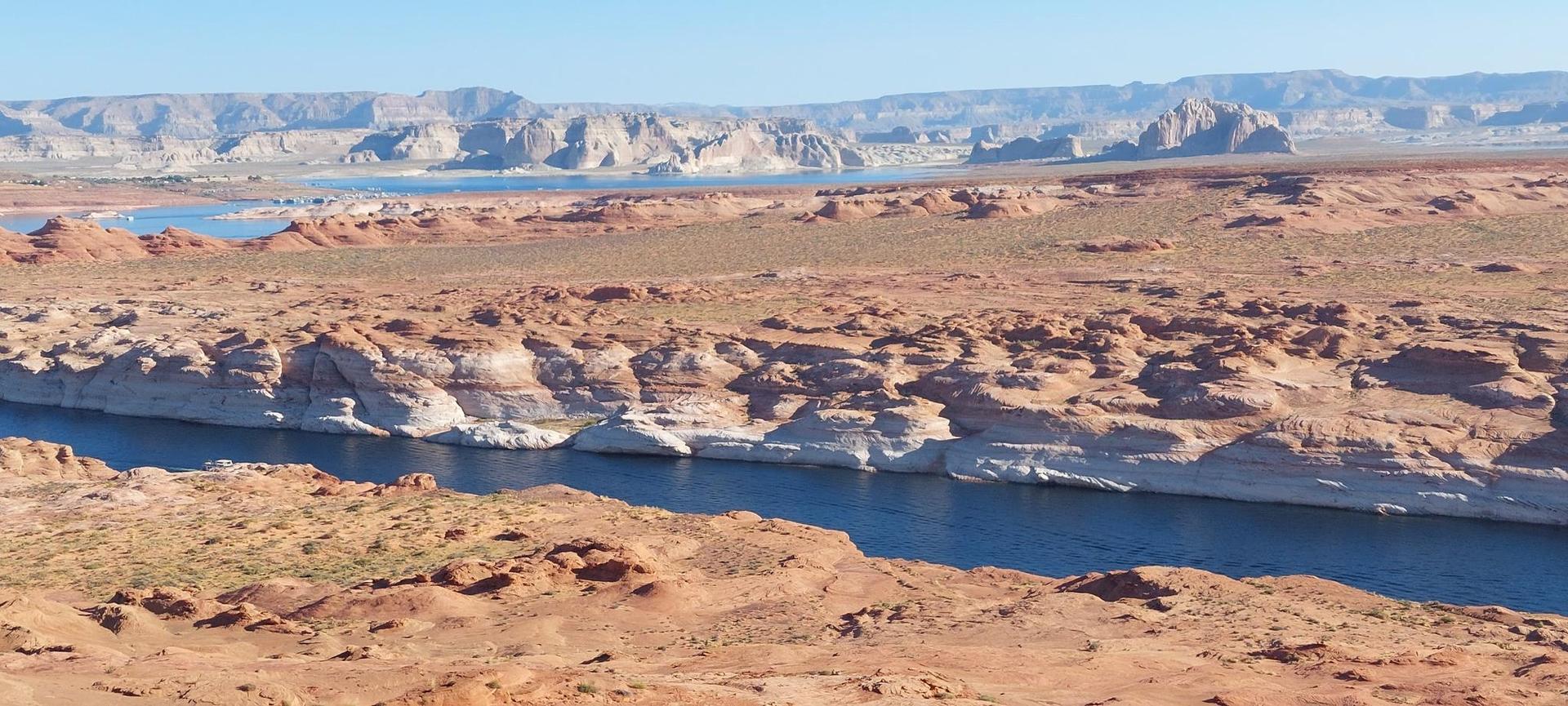 Blue river flows through light-colored rock formations in a desert landscape.