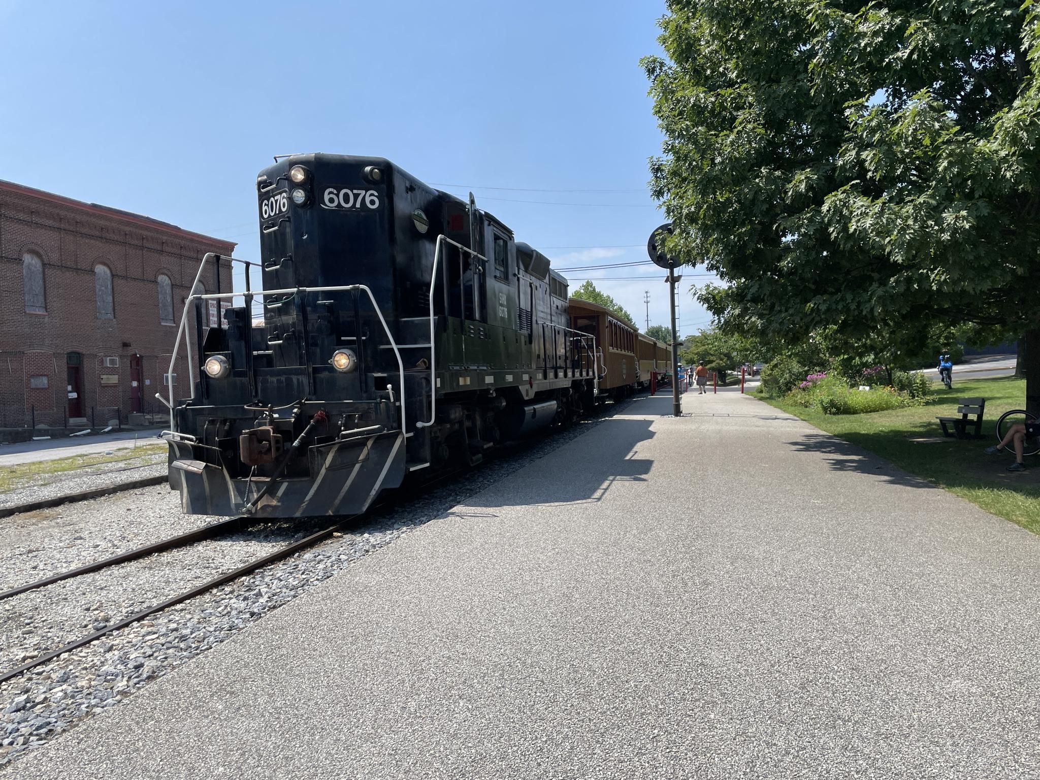 Large black train engine on tracks next to a paved platform. - York County Heritage Rail Trail
