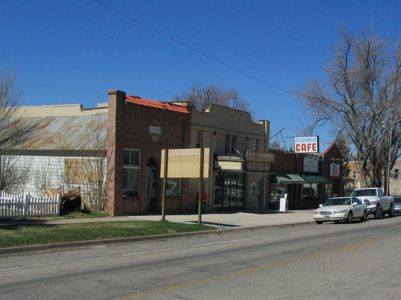 A street with parked cars in front of old brick and stucco buildings. - Enoch to Parrowan loop
