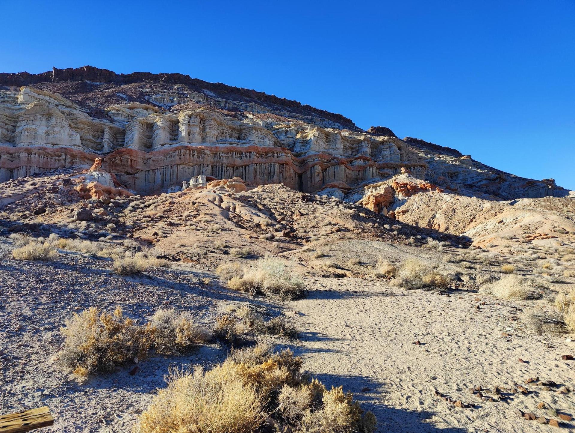 Arid landscape with eroded rock formations under a clear, sunny sky.