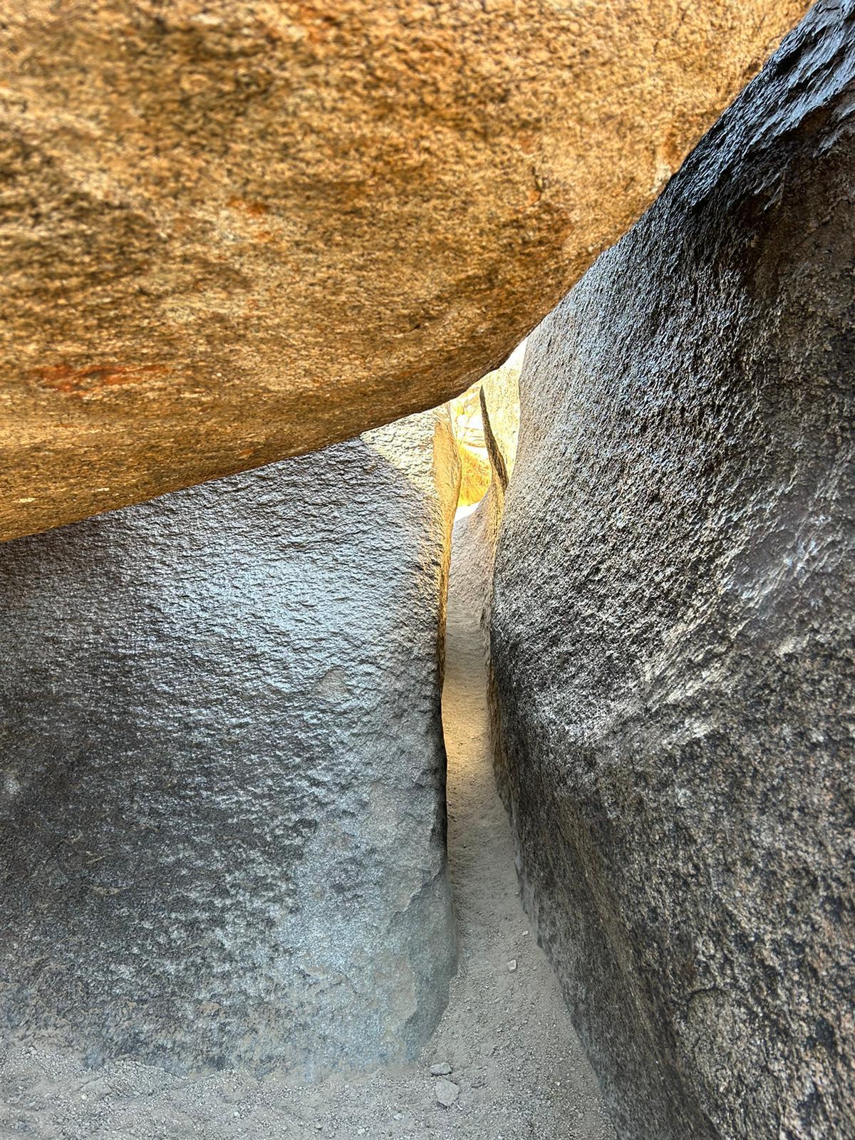 Narrow, dark crevice between large, light-colored boulders.