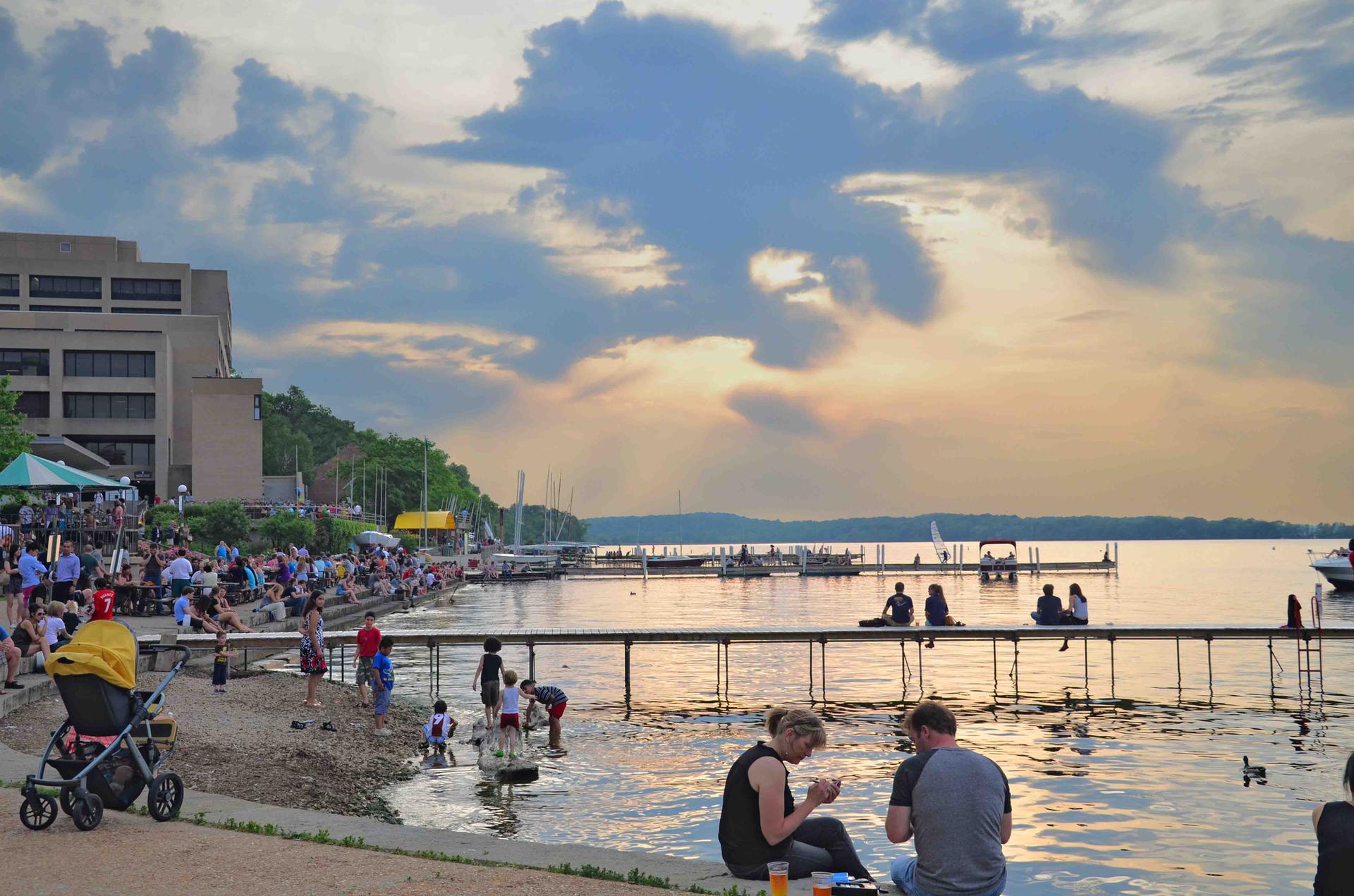 Many people enjoying a lively waterfront scene with a pier at sunset.