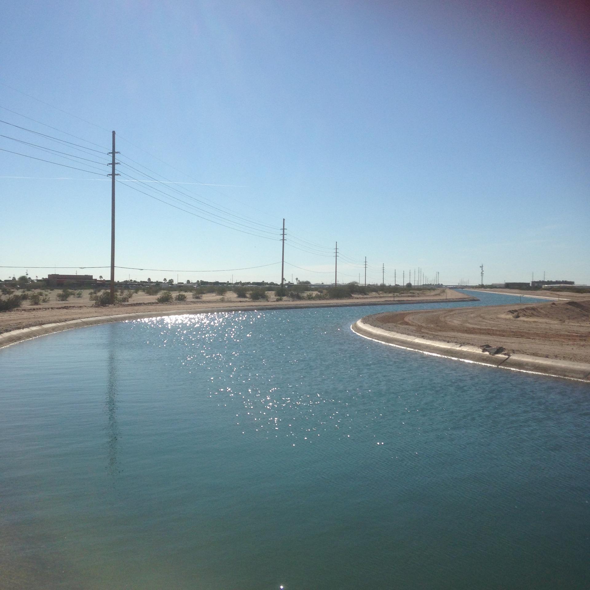 Wide canal with sparkling blue water under a clear, sunny sky.