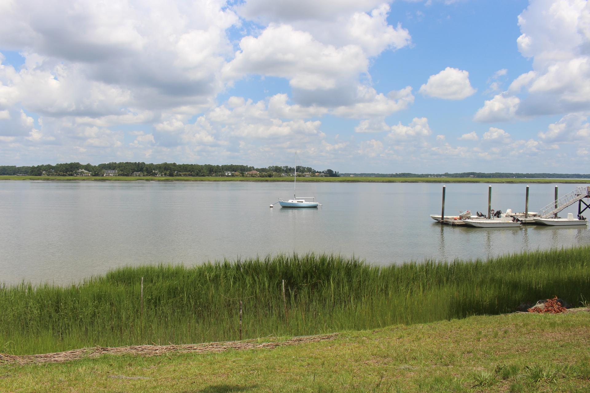 A wide river with a boat and docks, framed by green grass.