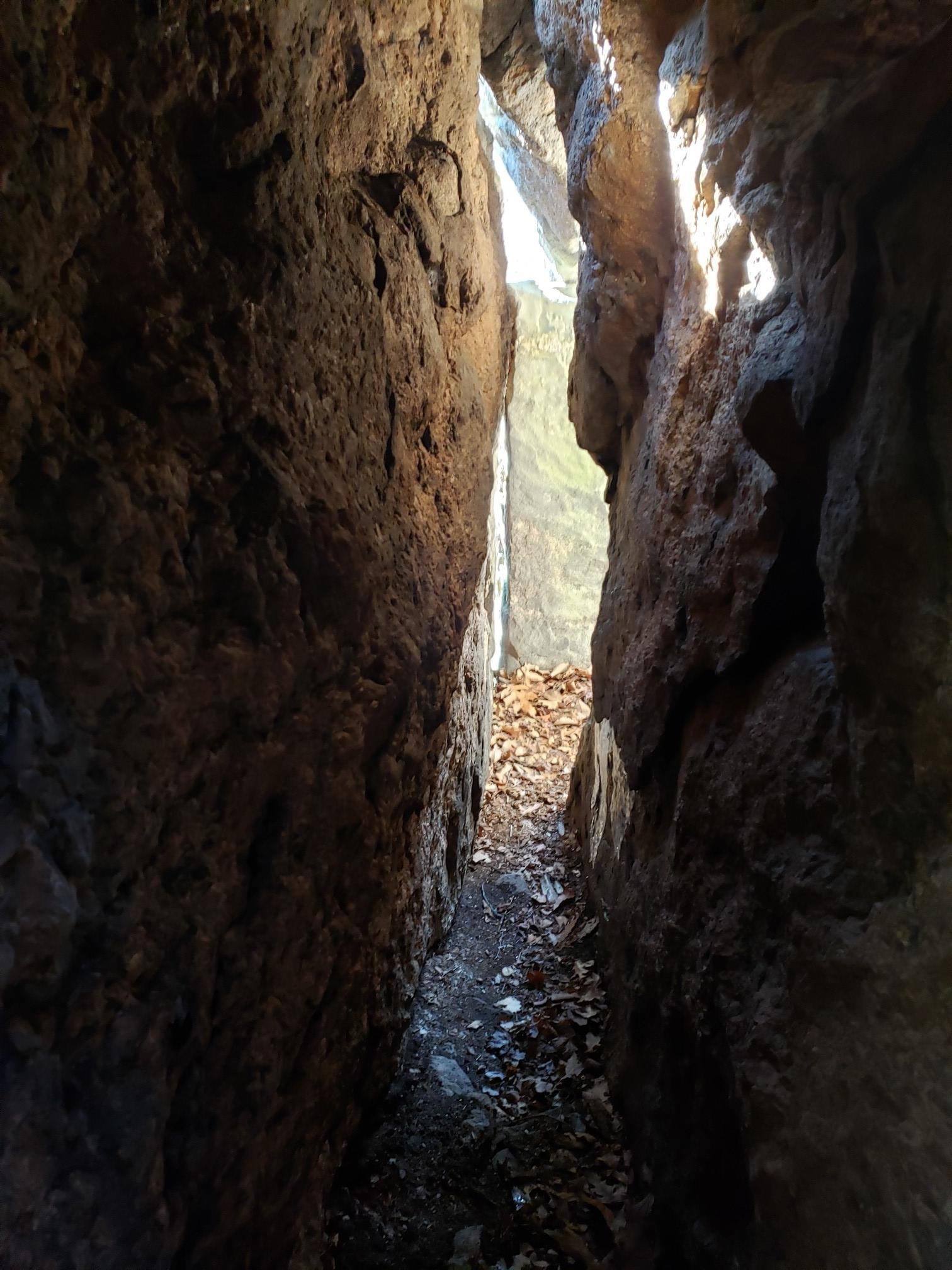 Narrow, dark rock crevice with light visible at the far end.
