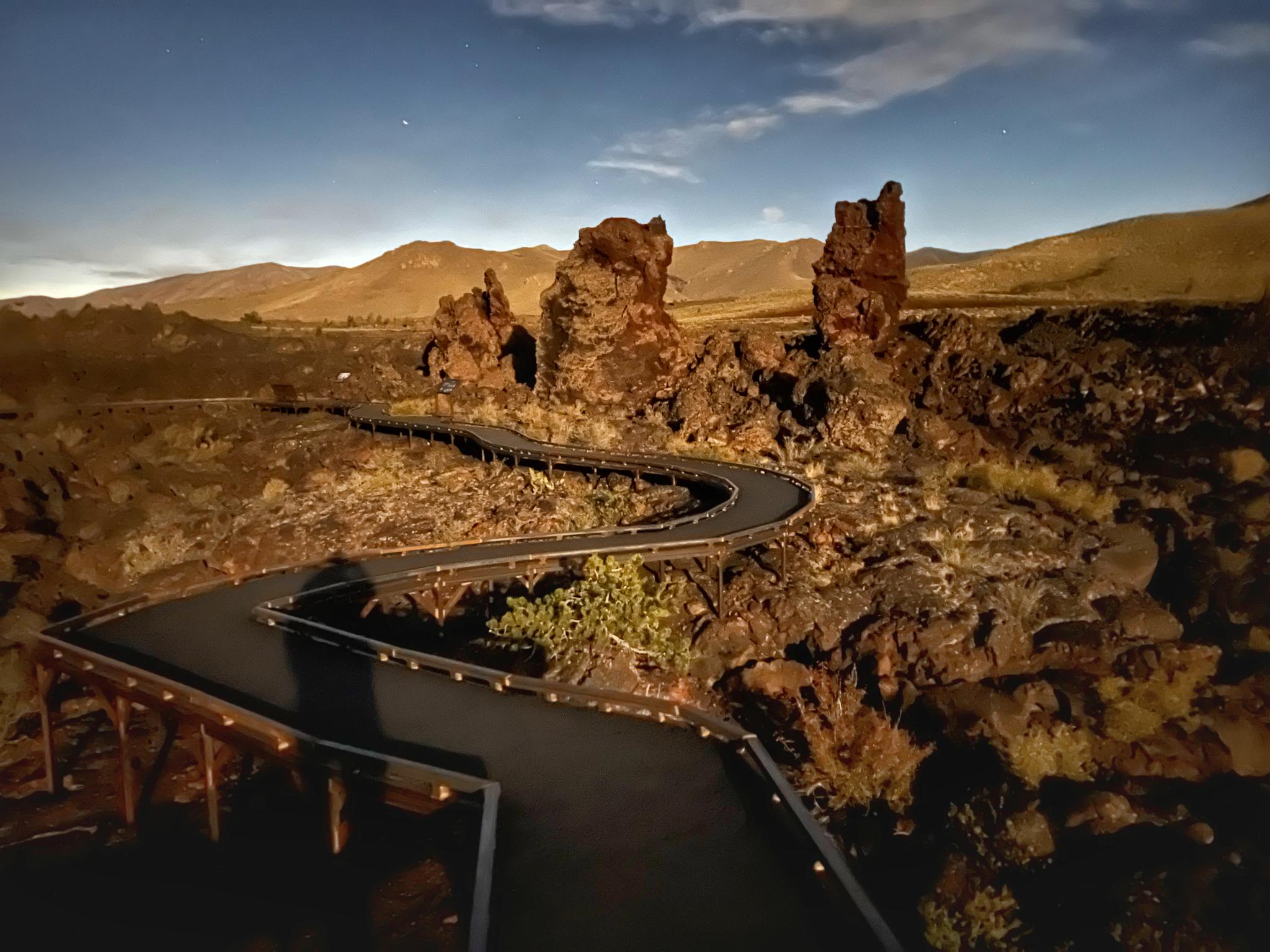 Winding boardwalk through dark volcanic rock pillars under a twilight sky.