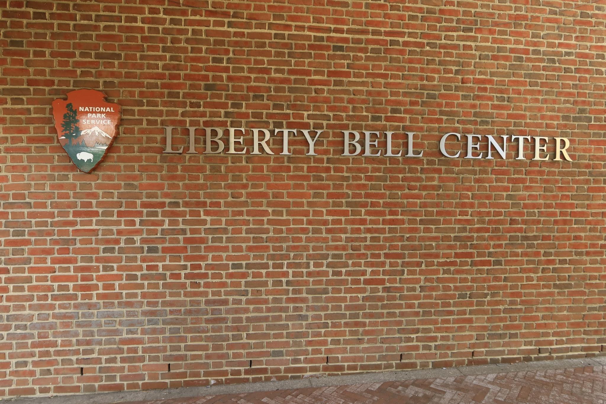 A brick wall with a sign reading 'LIBERTY BELL CENTER' and a park emblem.